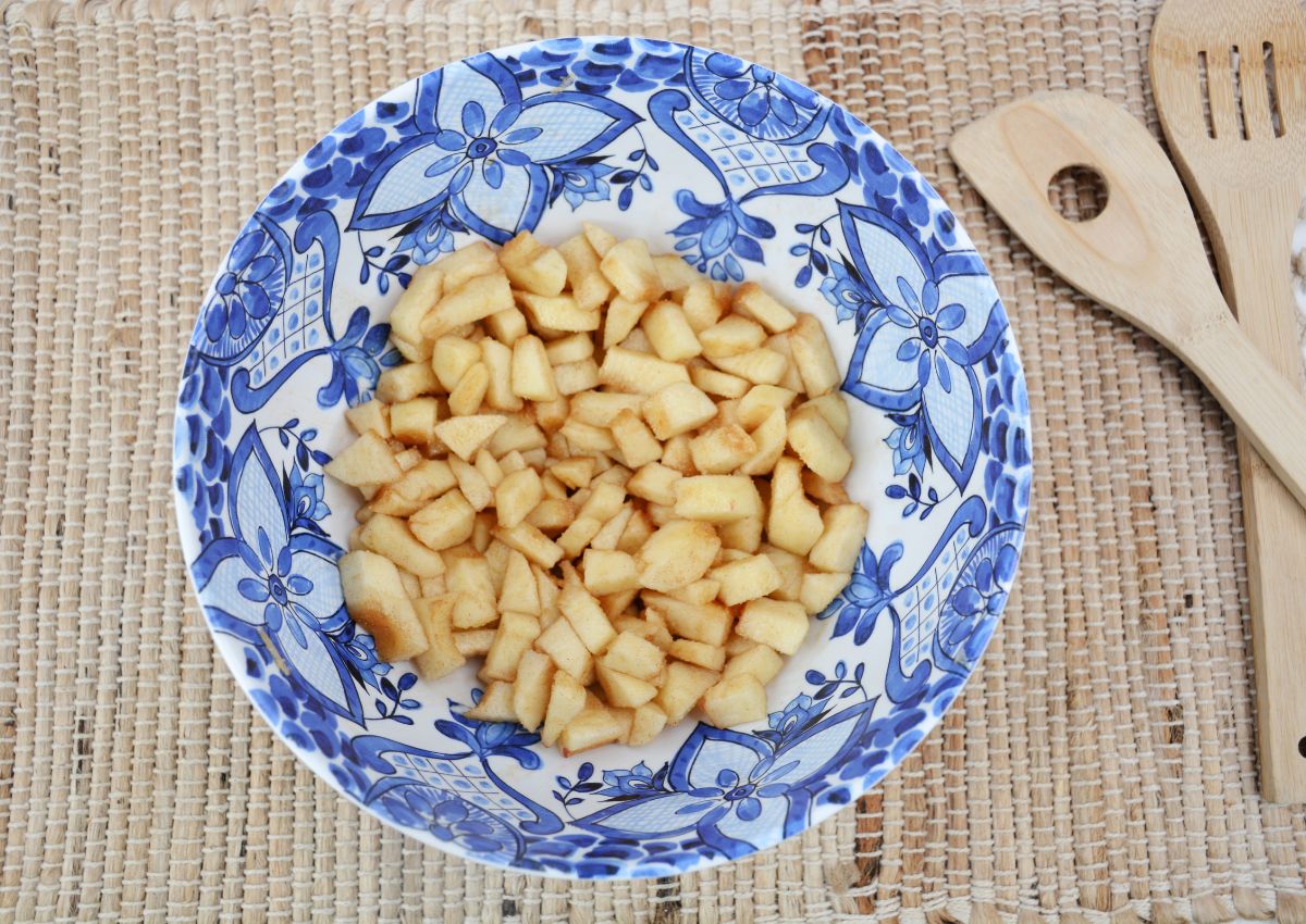 diced apples being coated in cinnamon sugar in a large bowl.