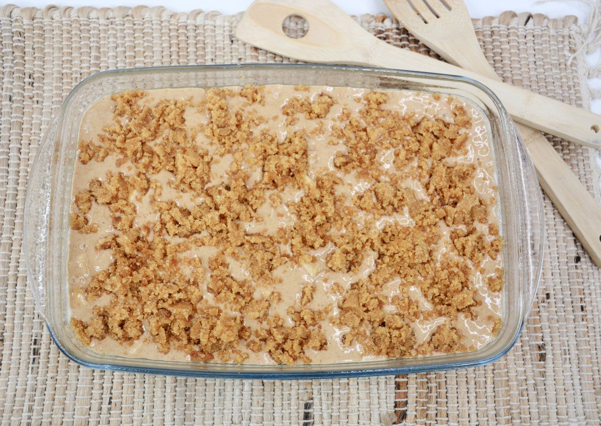 finished apple cake in a glass casserole dish ready for you the oven.