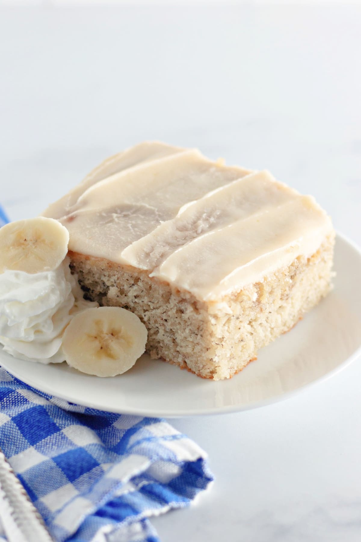 slice of banana cake with brown butter frosting on a plate.