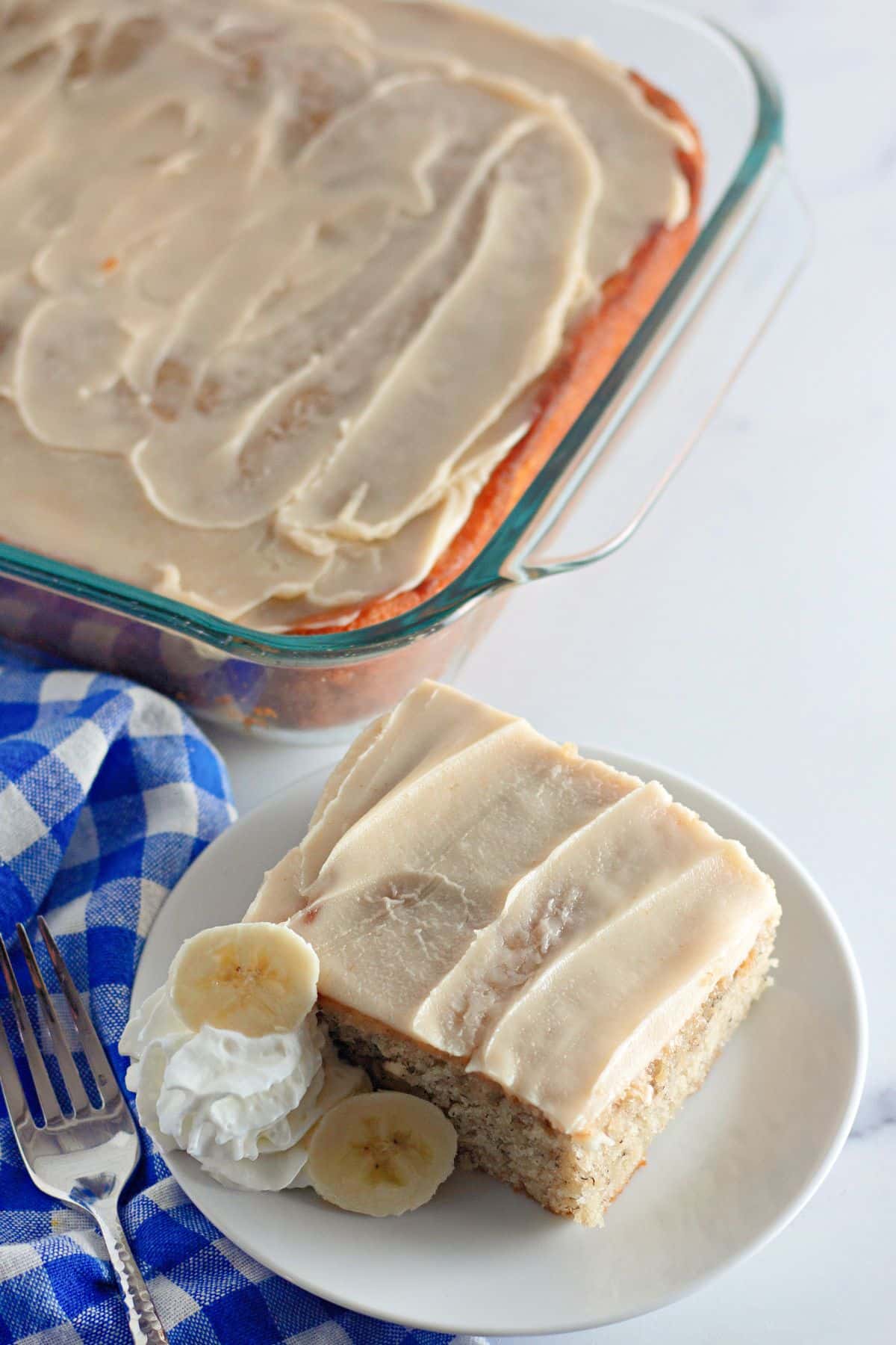 slice of banana cake with brown butter frosting on a plate.