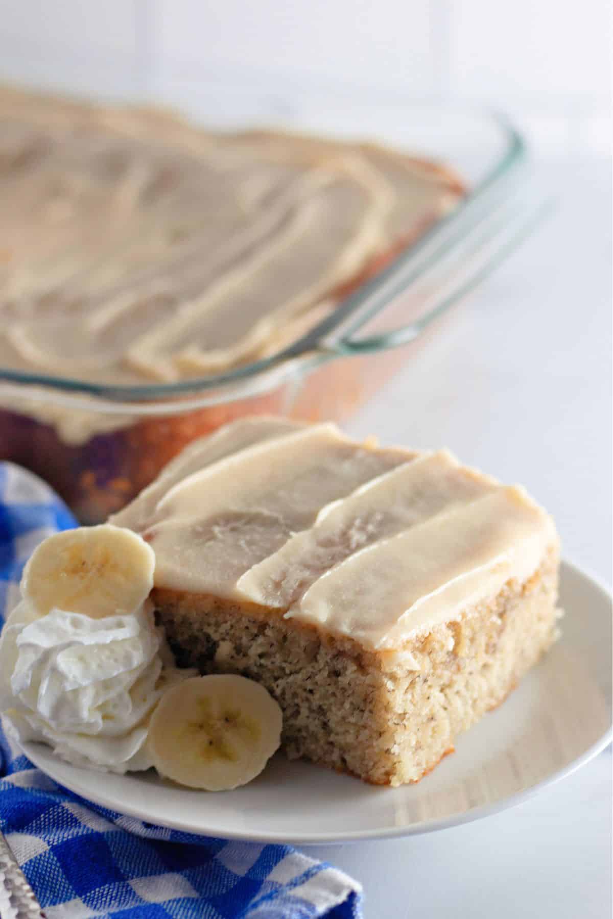 slice of banana cake with brown butter frosting on a plate.