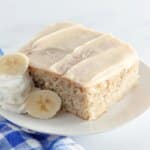 slice of banana cake with brown butter frosting on a plate.