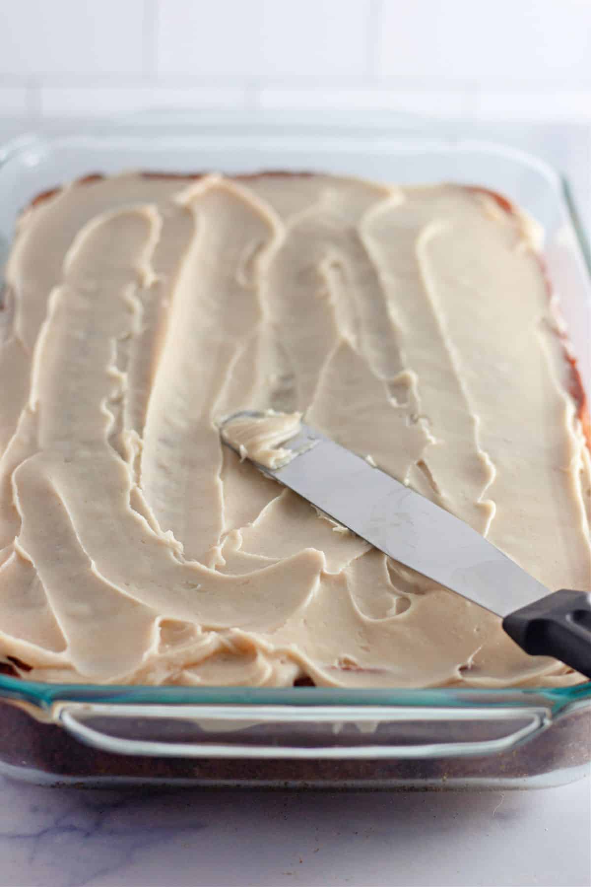 frosting being spread on top of the cake with a knife.