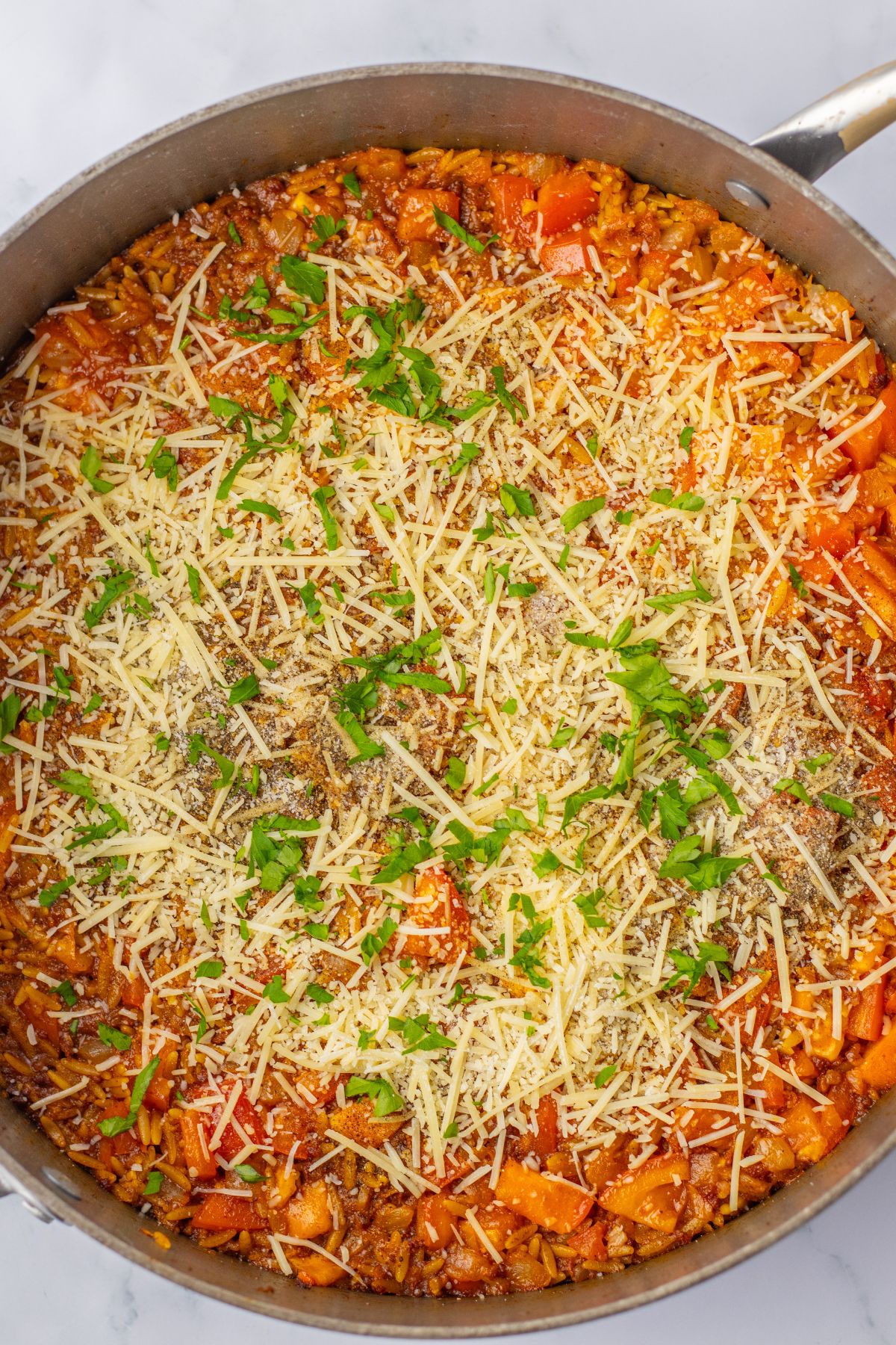 large skillet full of cheesy tomato chorizo orzo.
