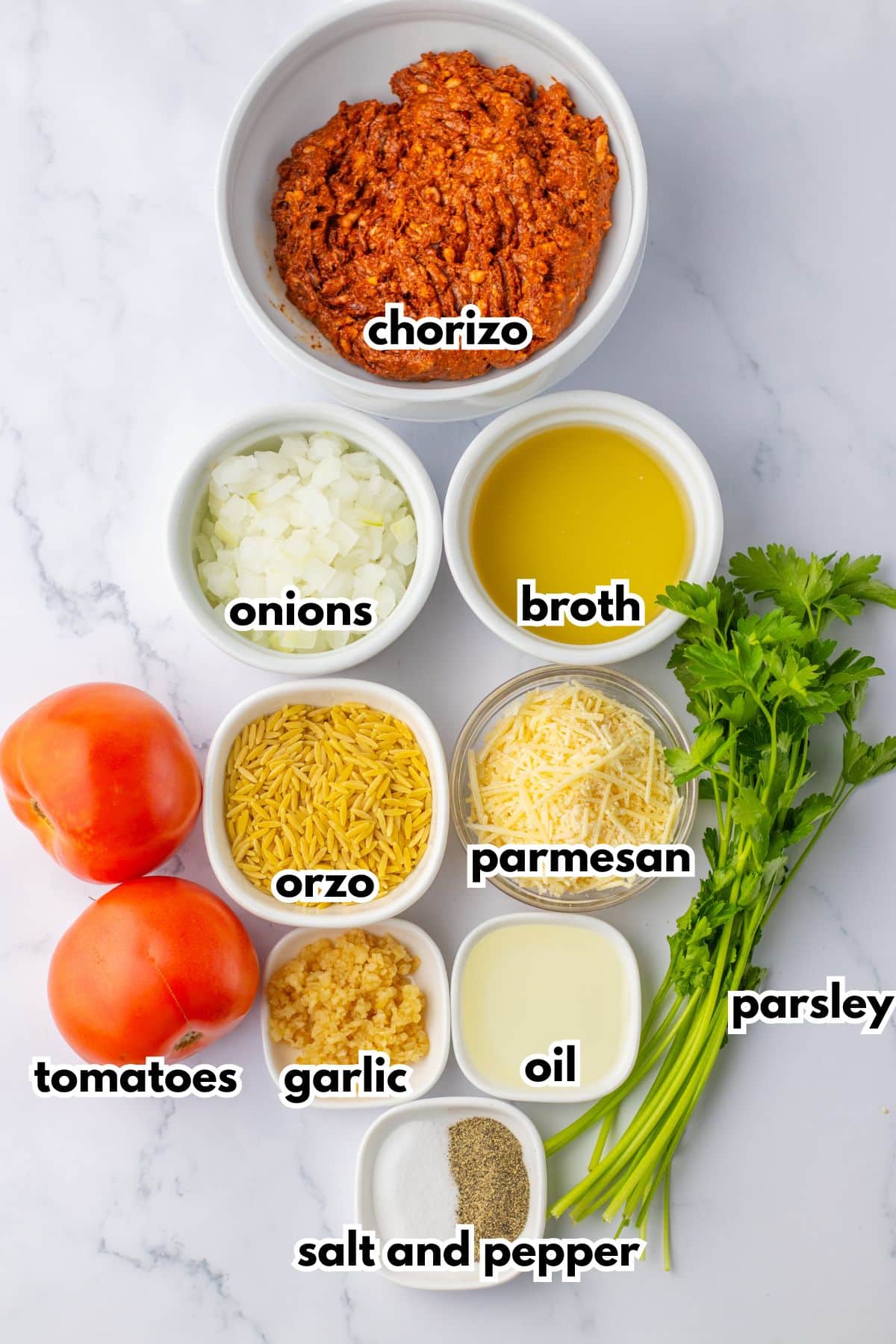 bowls of chorizo, onions, broth, orzo, parmesan, garlic, oil, salt, pepper, parsley, and tomatoes on a counter.