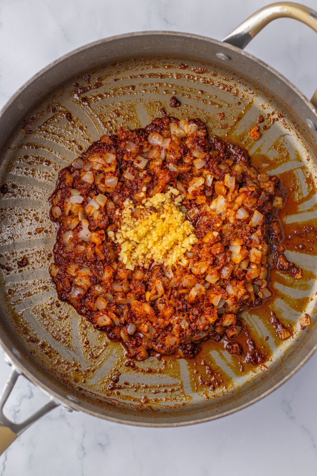 chorizo, onions, and garlic being cooked in a skillet.