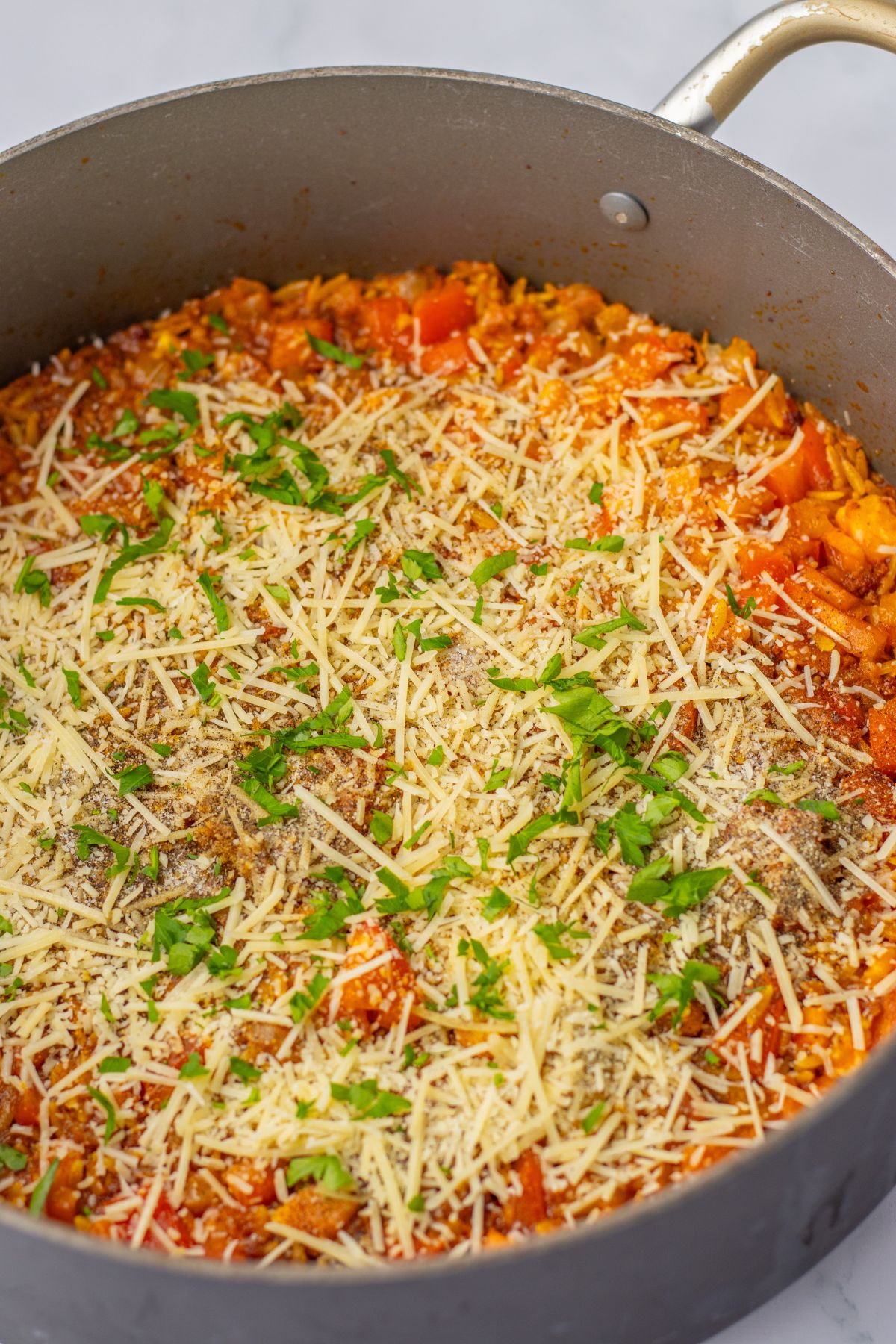 large skillet full of cheesy tomato chorizo orzo.
