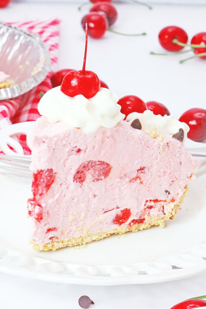 slice of chocolate cherry pie topped with whipped cream and a cherry on a plate.