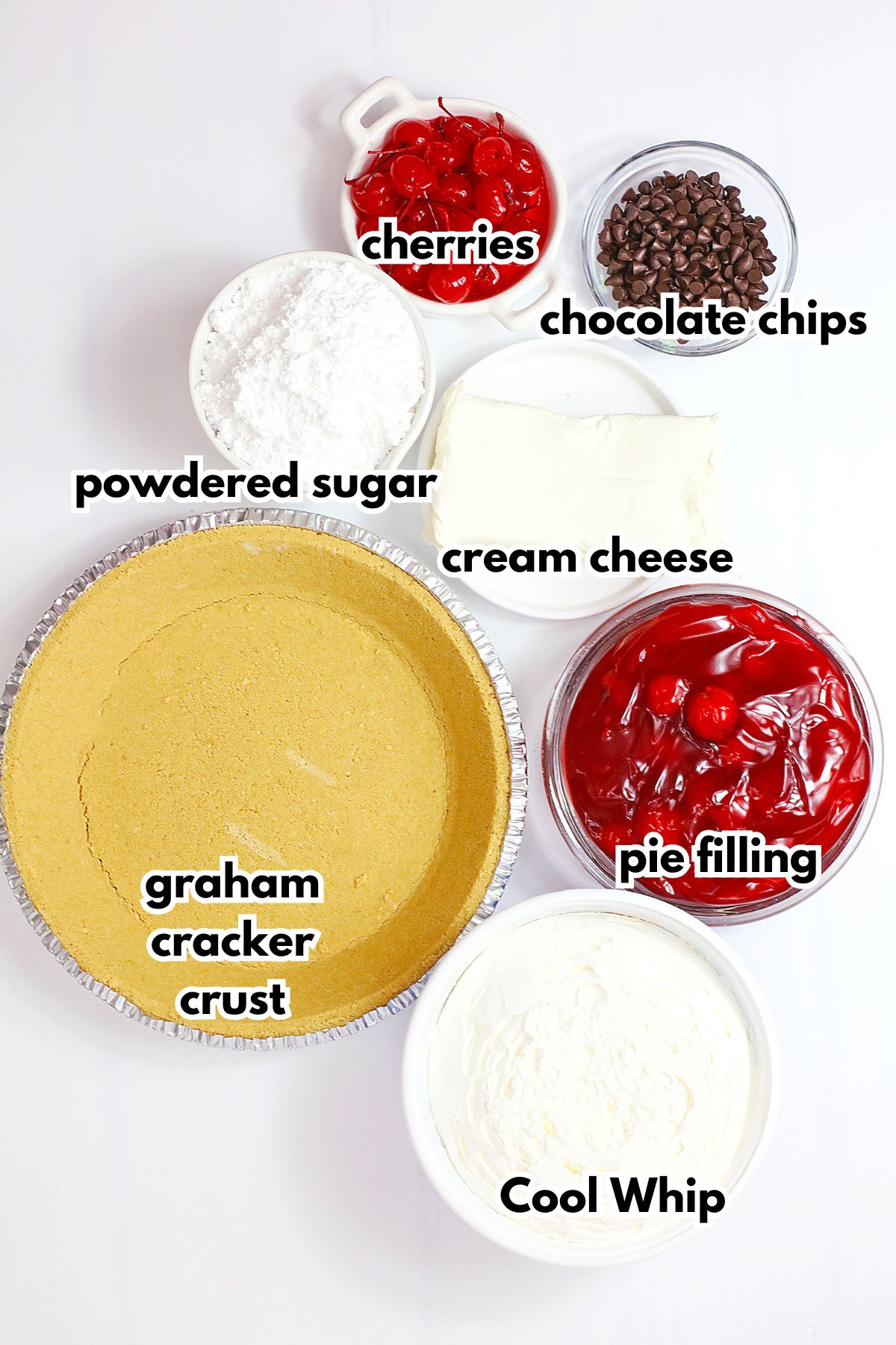 bowls of cherries, powdered sugar, cream cheese, chocolate chips, graham cracker crust, cool whip, and pie filling on a counter.