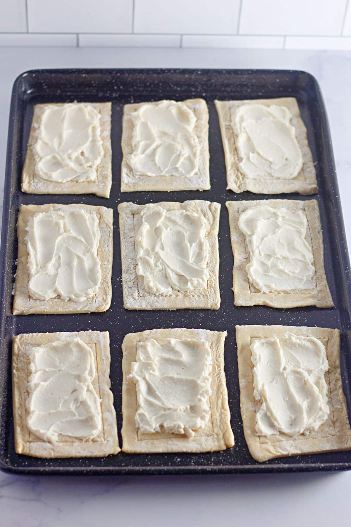 cream cheese being spread on top of puff pastry.