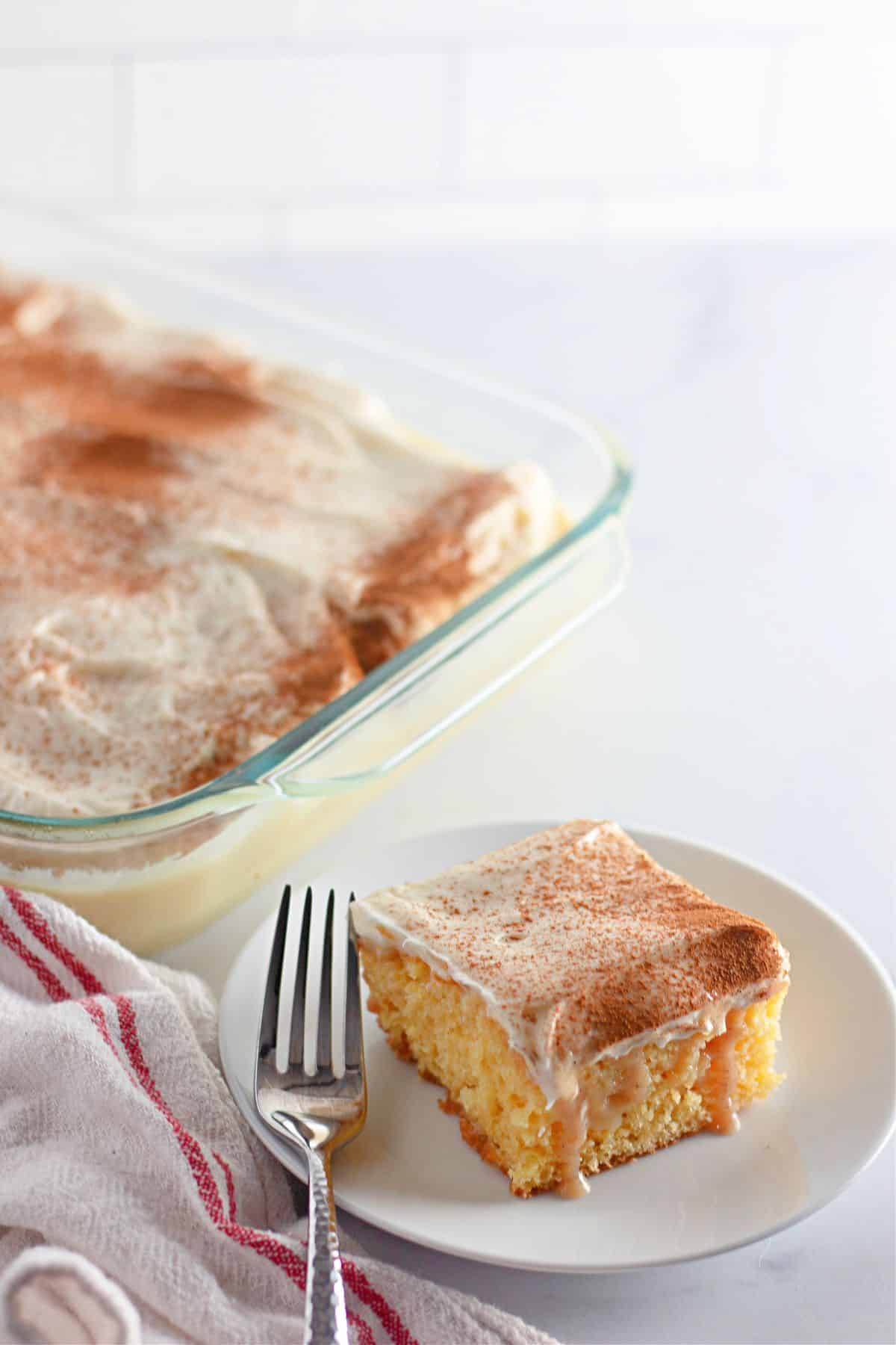 slice of cinnamon roll poke cake on a plate.