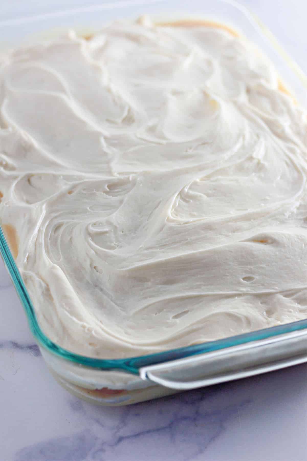 frosted cinnamon roll poke cake in a glass casserole dish.