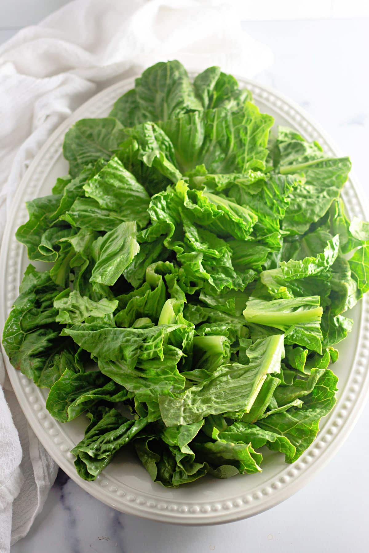 lettuce being added to a large serving platter.