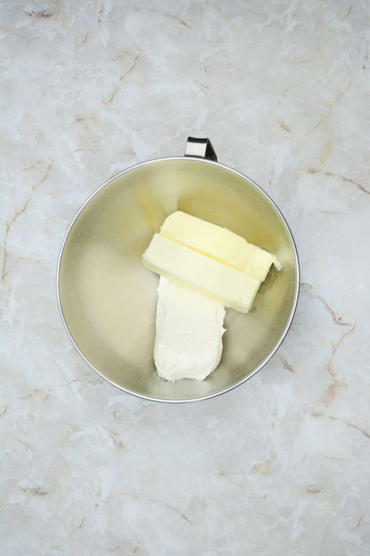 butter and cream cheese being mixed together in a stand mixer.