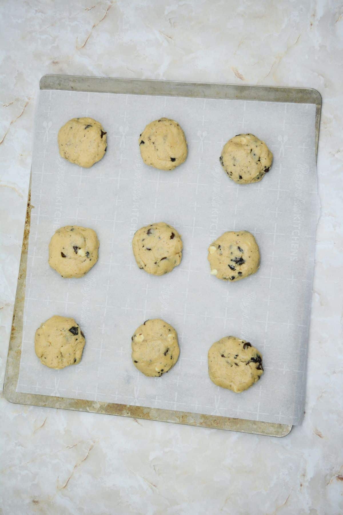 cookie dough balls on a parchment lined cookie sheet.