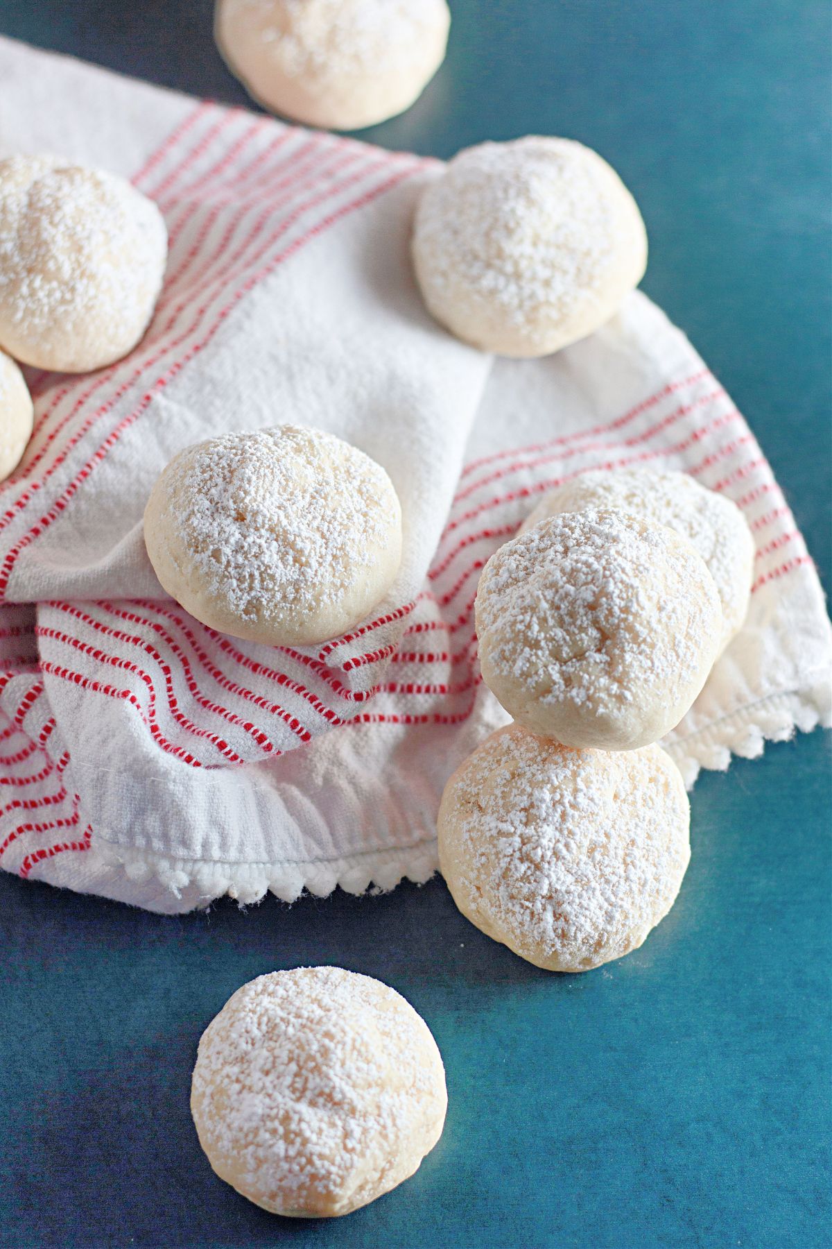 cream cheese snowball cookies laid out on a kitchen towels on the counter.