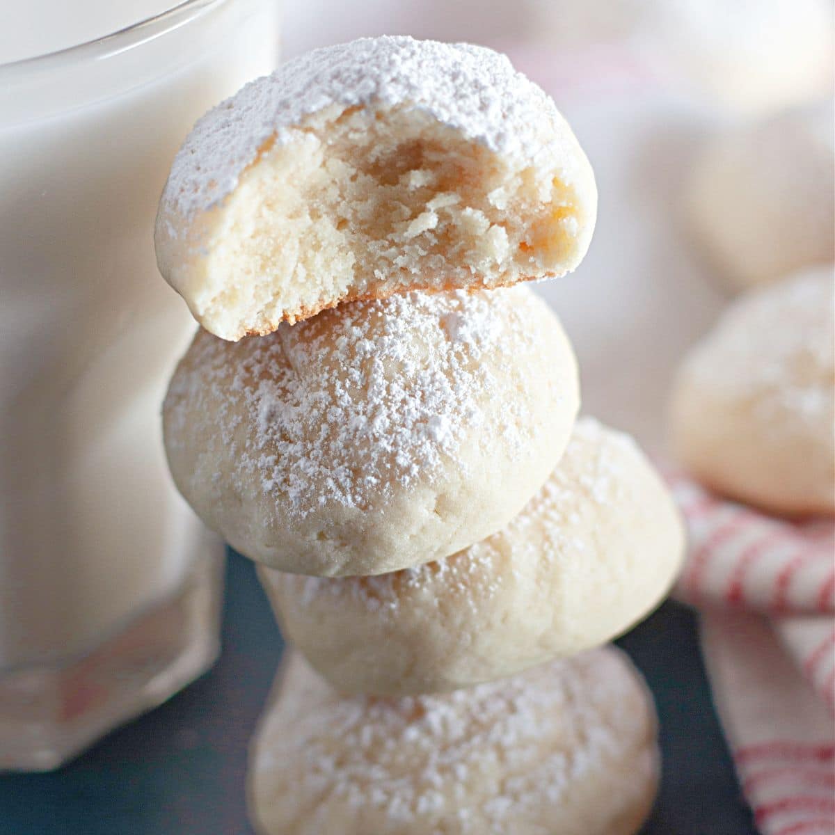 four cream cheese snowball cookies stacked on top of each other.