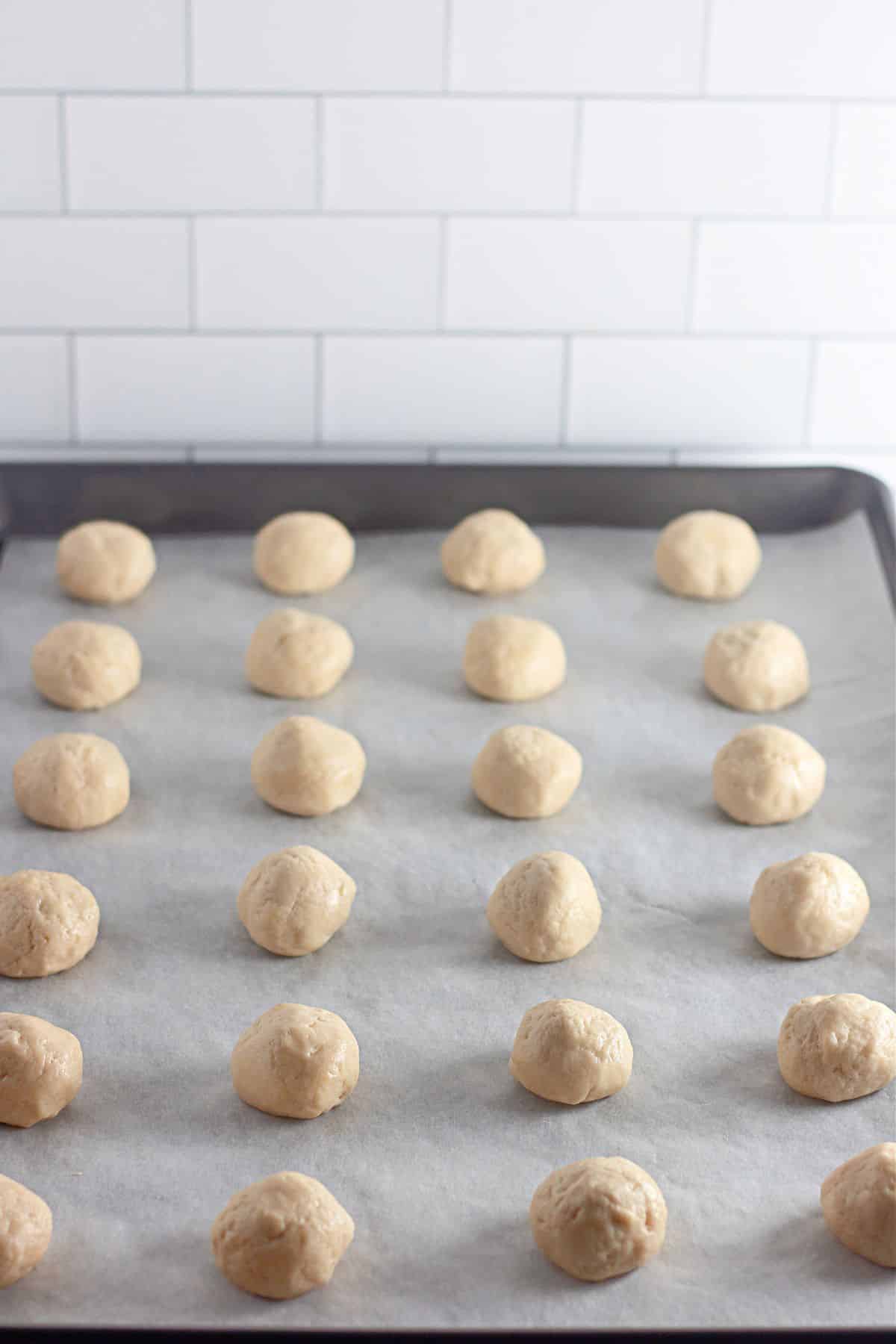 cookie dough balls on a parchment lined baking sheet ready for the oven.