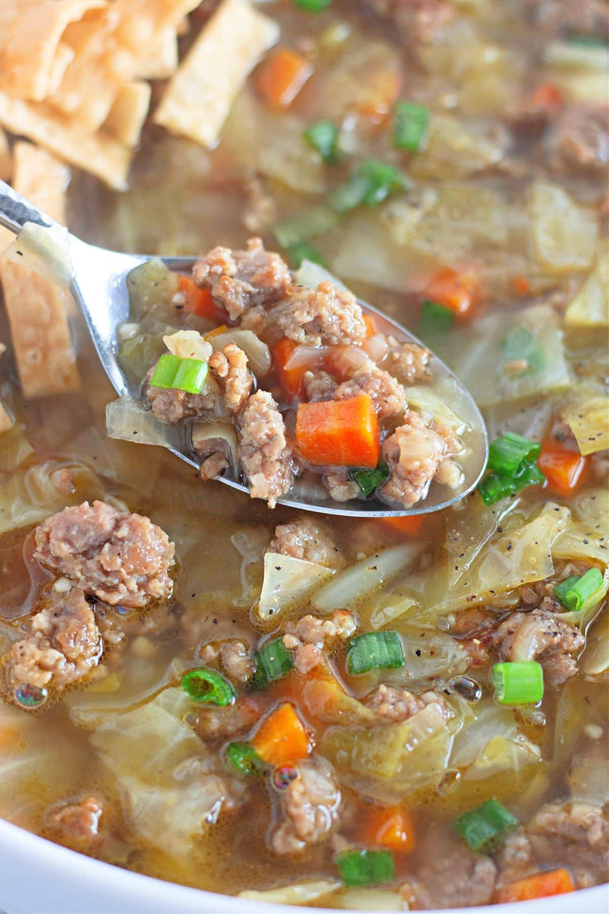 spoonful of eggroll soup held in the air above the soup.