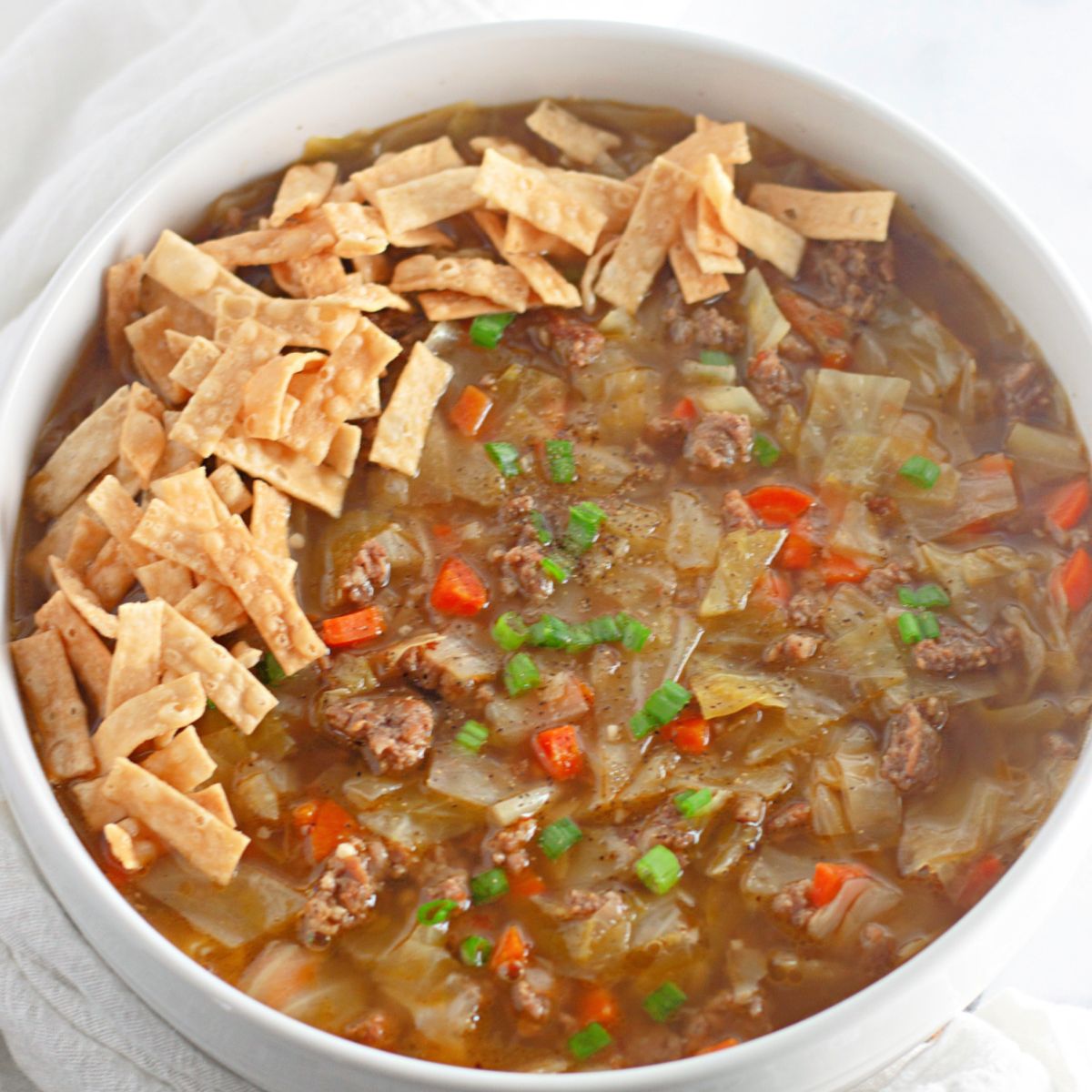 large bowl filled with wonton soup and garnished with tortilla strips.