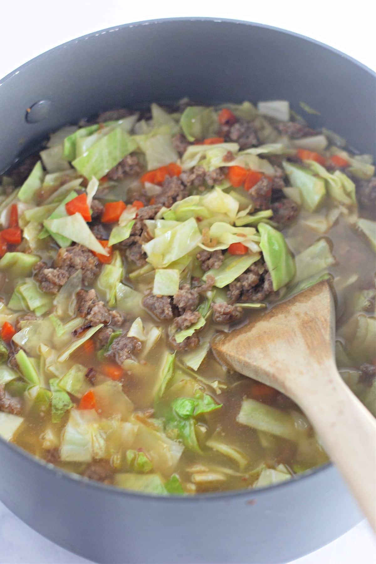 broth and seasonings being added to a large stock pot.