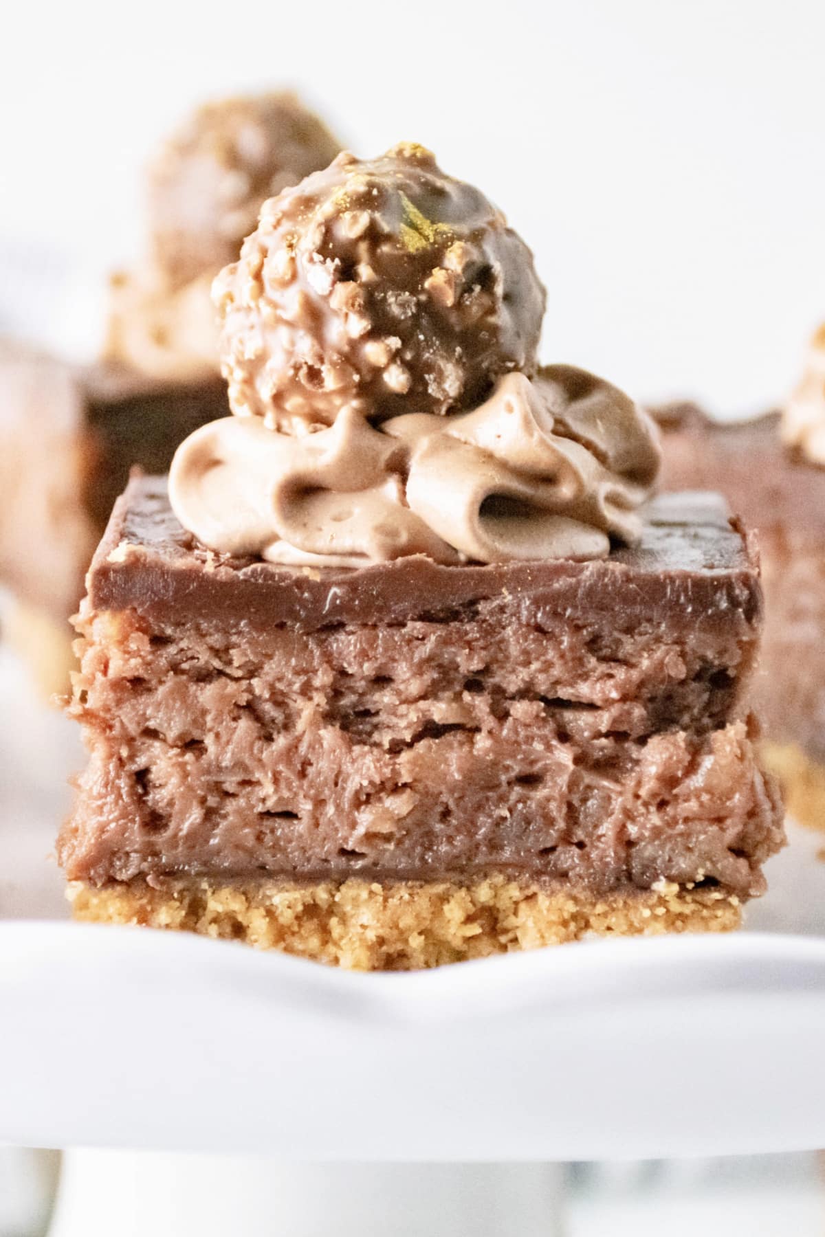 ferrero rocher cheesecake bars on a cake plate.