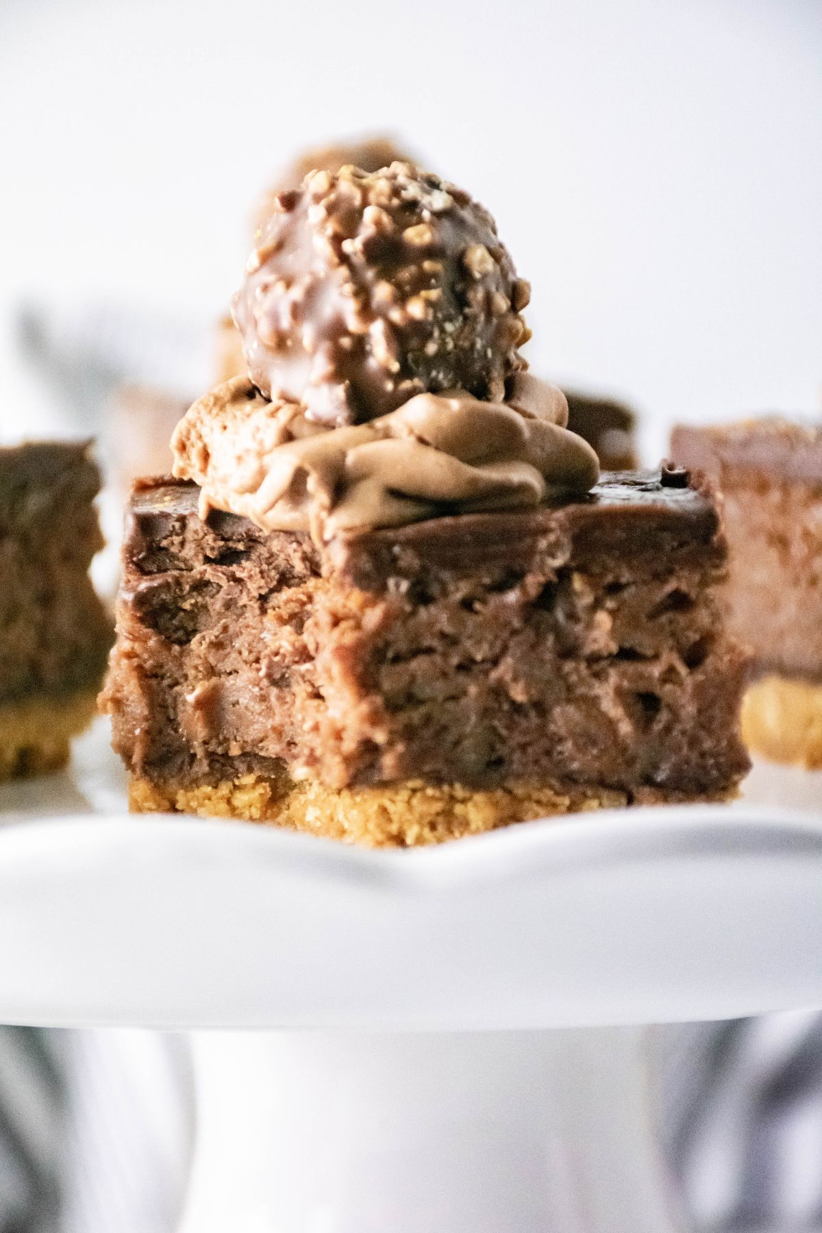 ferrero rocher cheesecake bars on a cake plate.