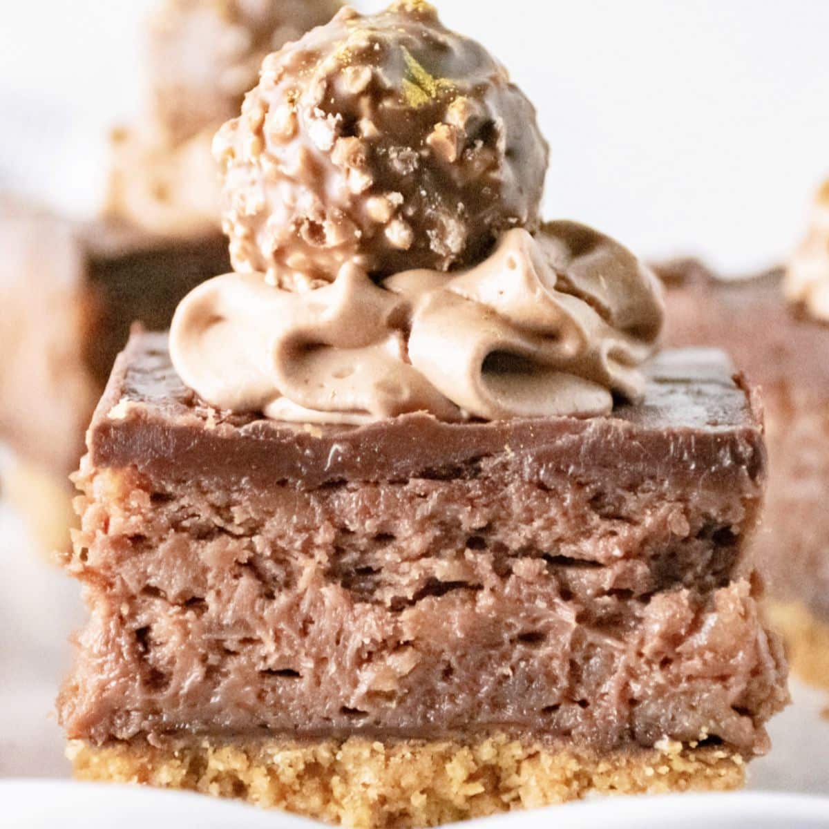 ferrero rocher cheesecake bars on a cake plate.