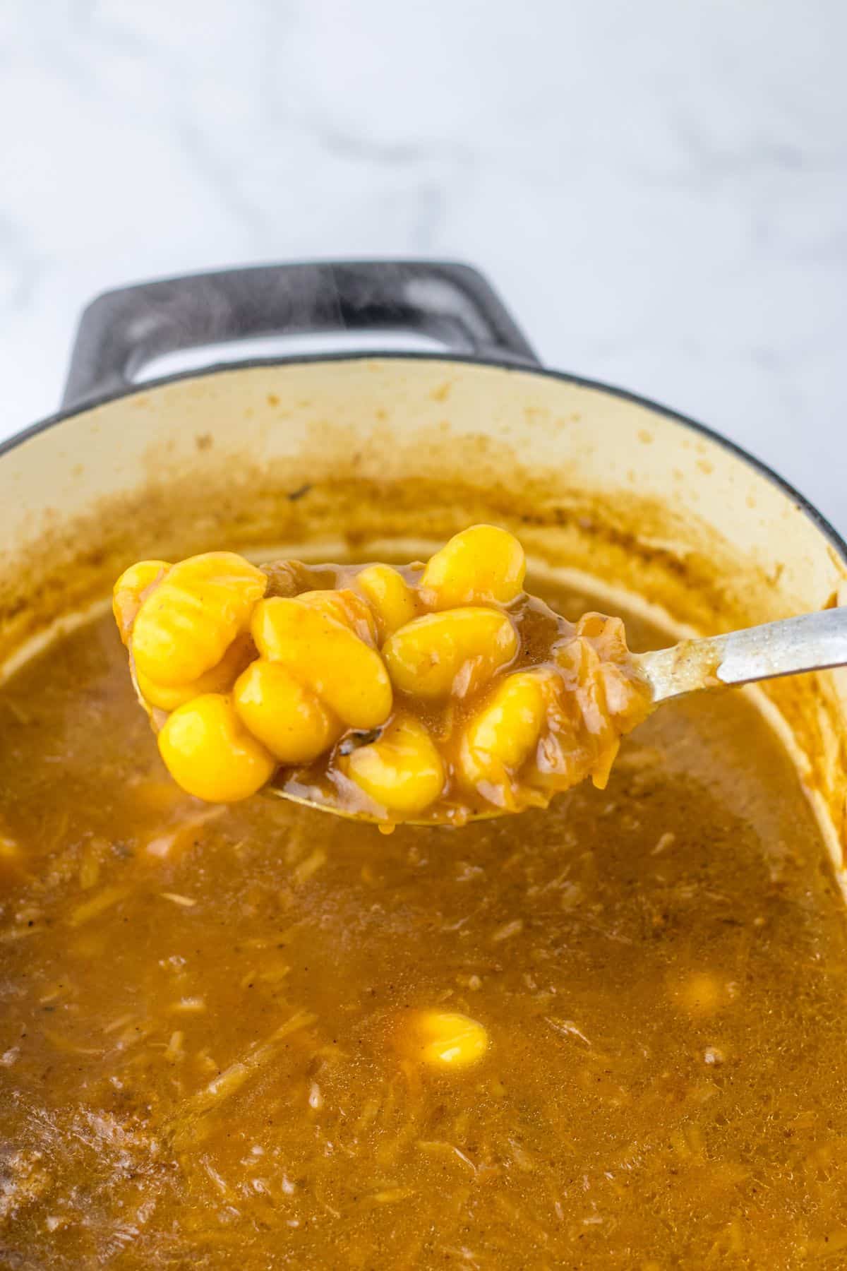 gnocchi being added to a pot of soup.
