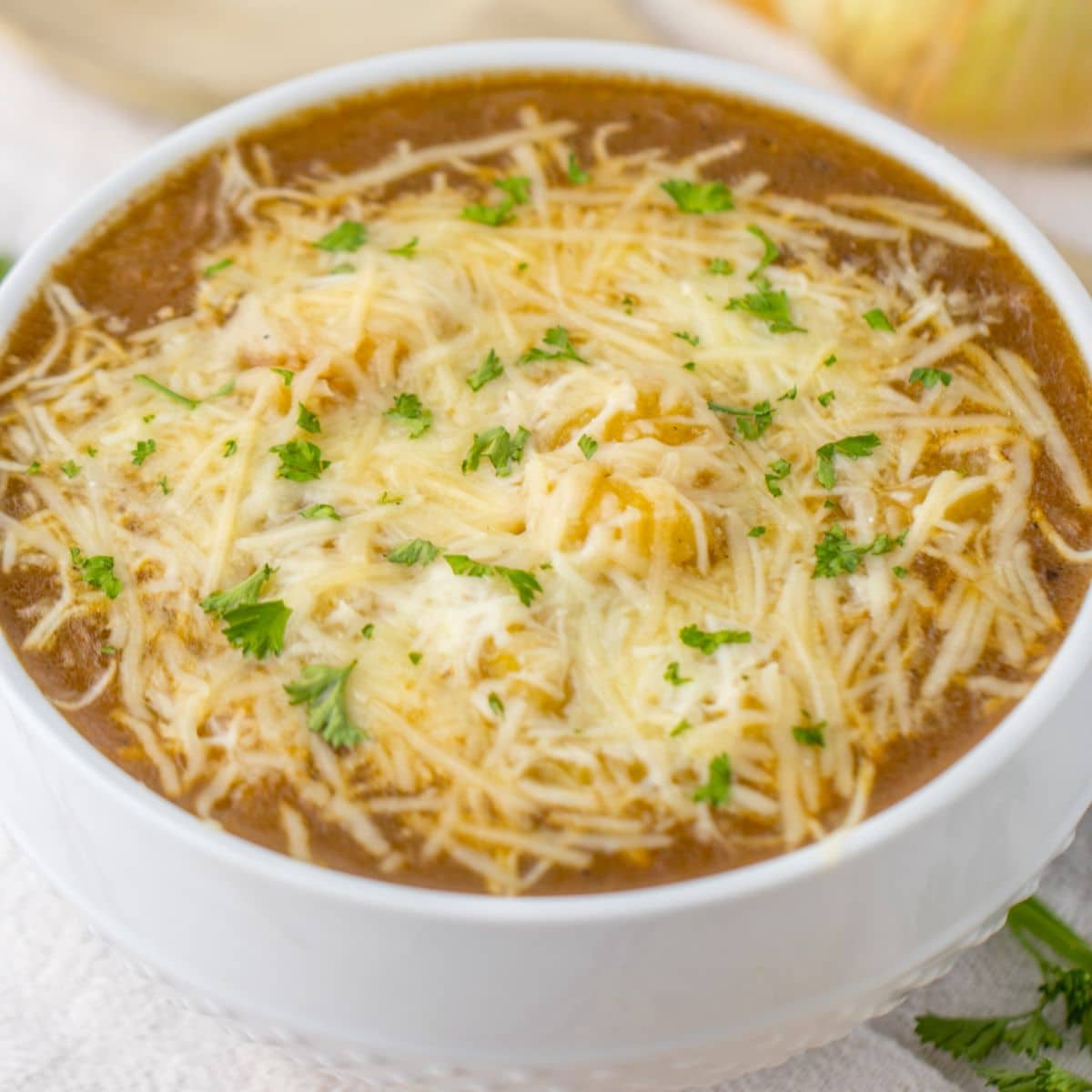 bowl full of french onion gnocchi and topped with cheese and parsley.