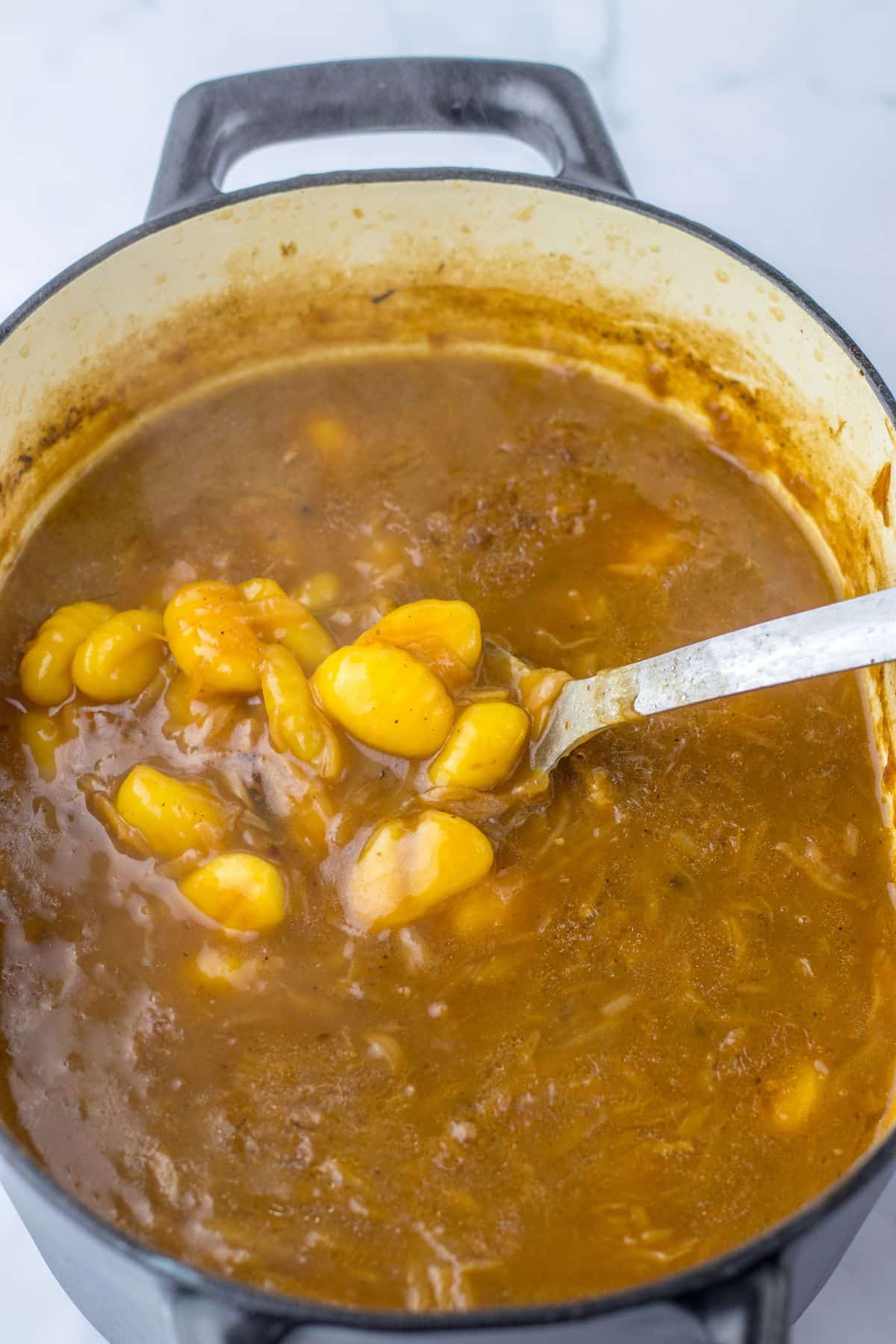 gnocchi being added to a pot of soup.