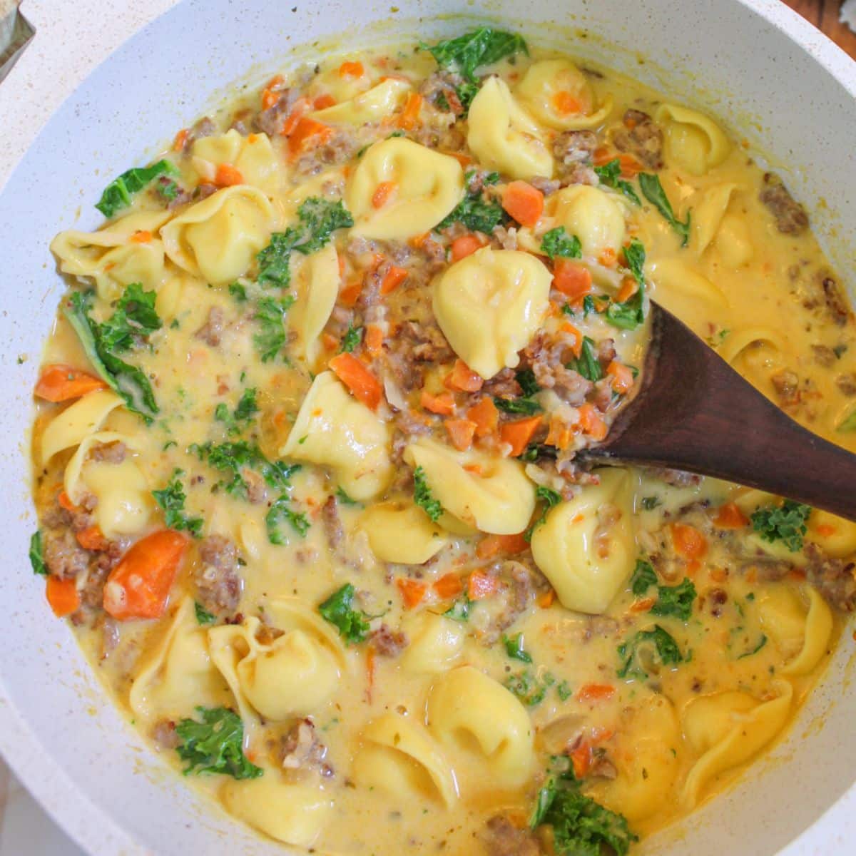 pot full of kale sausage tortellini soup garnished with kale.