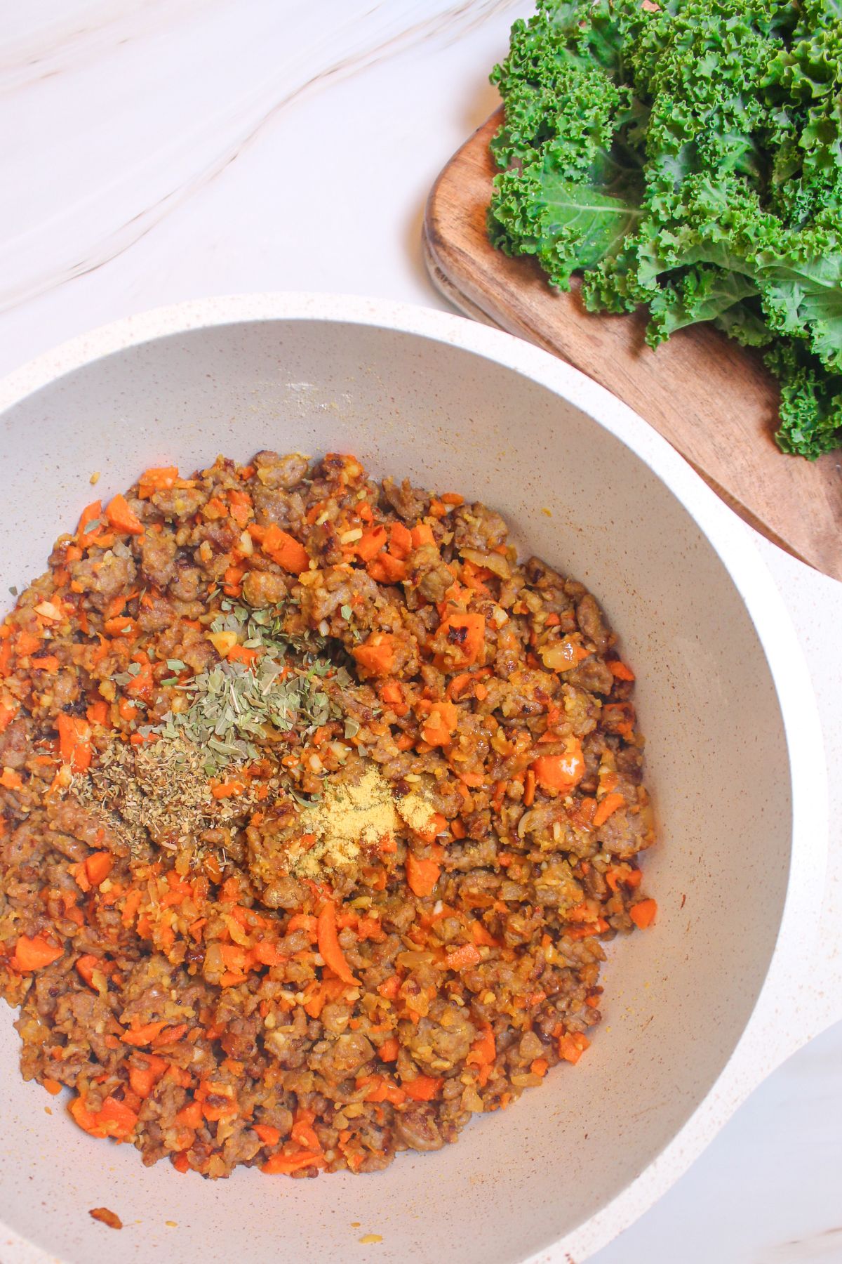 seasonings being added to cooked vegetables and sausage.