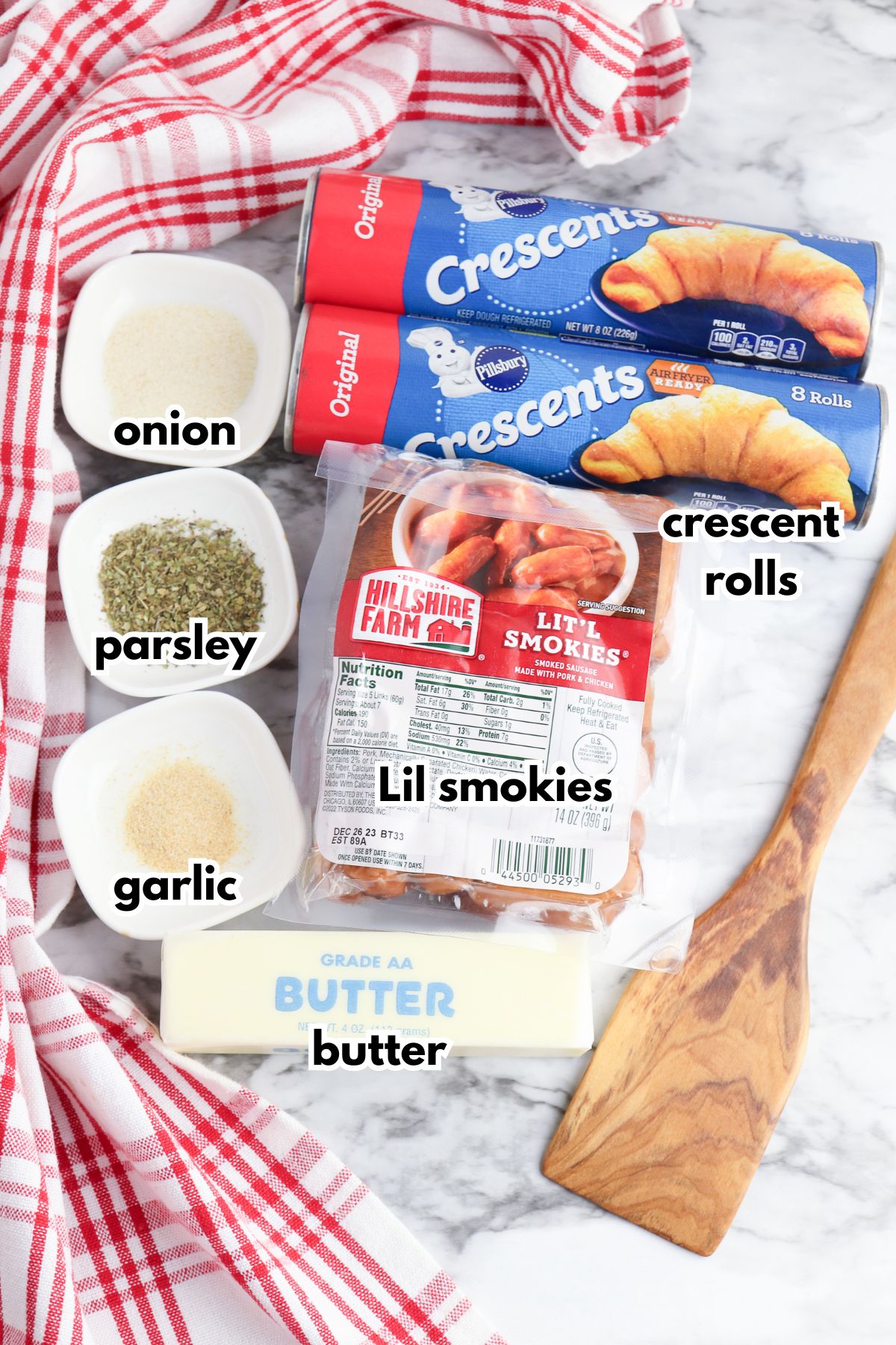 cans of crescent rolls, onion powder, parsley, garlic powder, lil smokies, and butter on a counter.