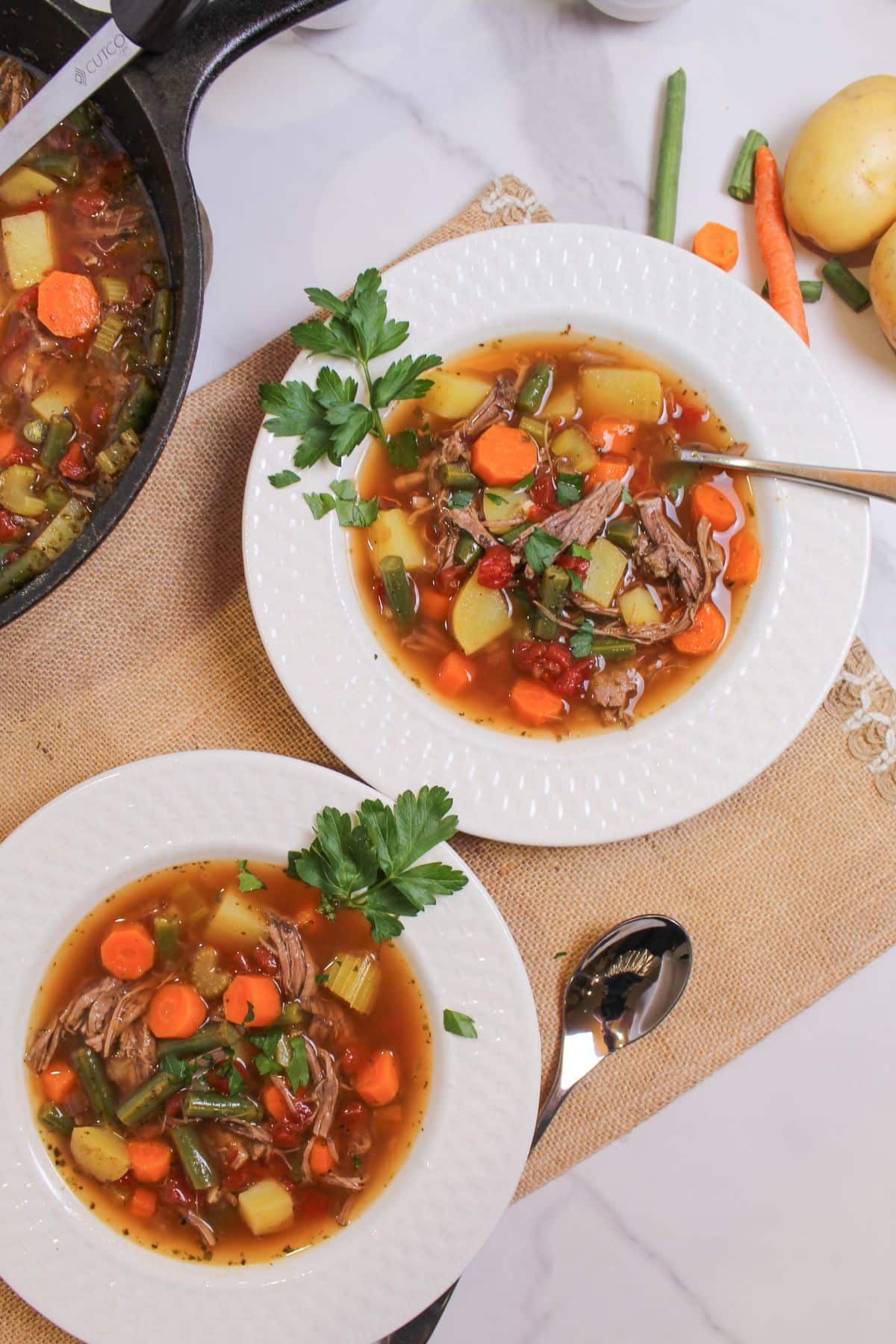 two bowls of pot roast vegetable soup on a table.