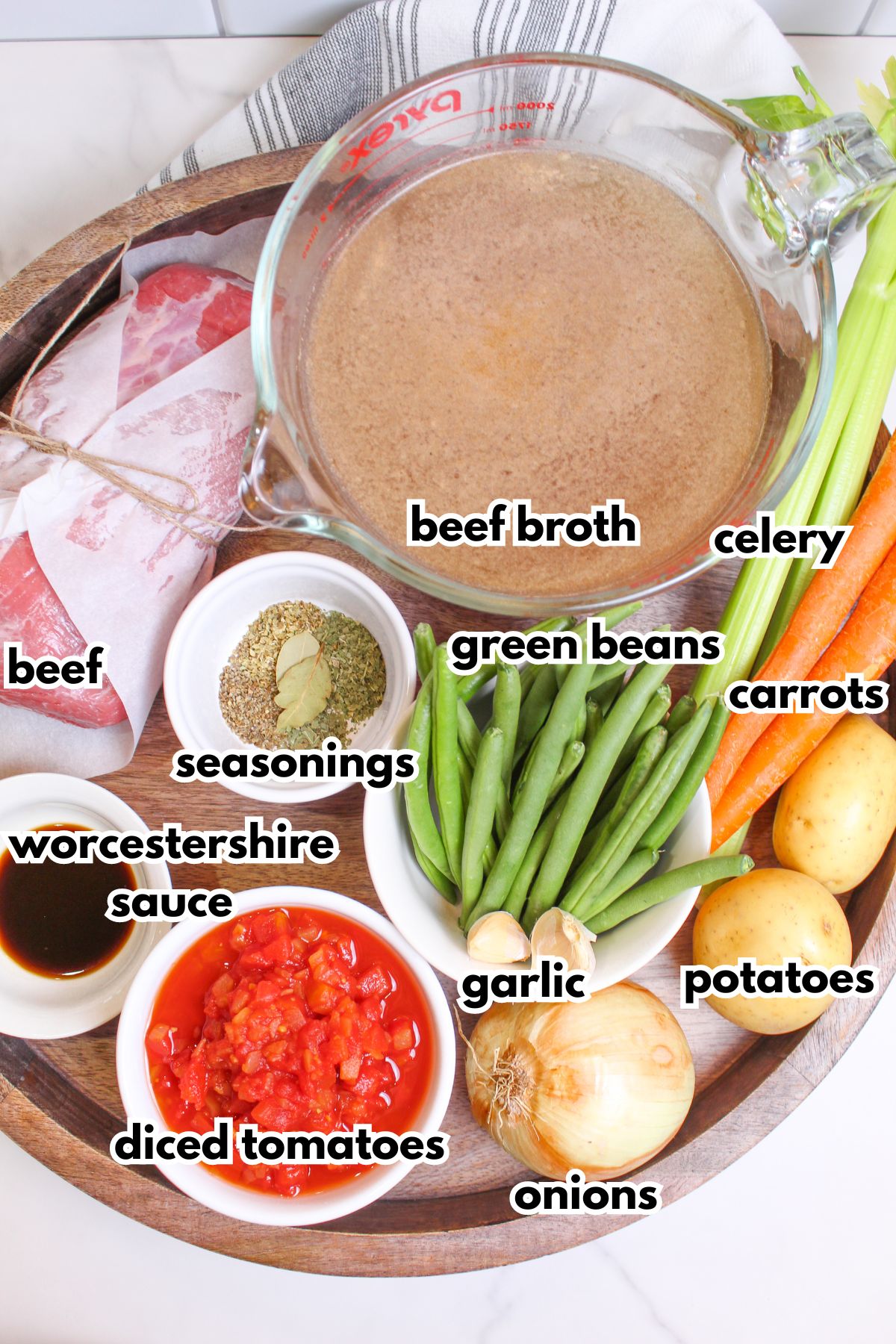 bowls of beef broth, beef, seasonings, worcestershire sauce, diced tomatoes, garlic, green beans, celery, carrots, potatoes, and onions.