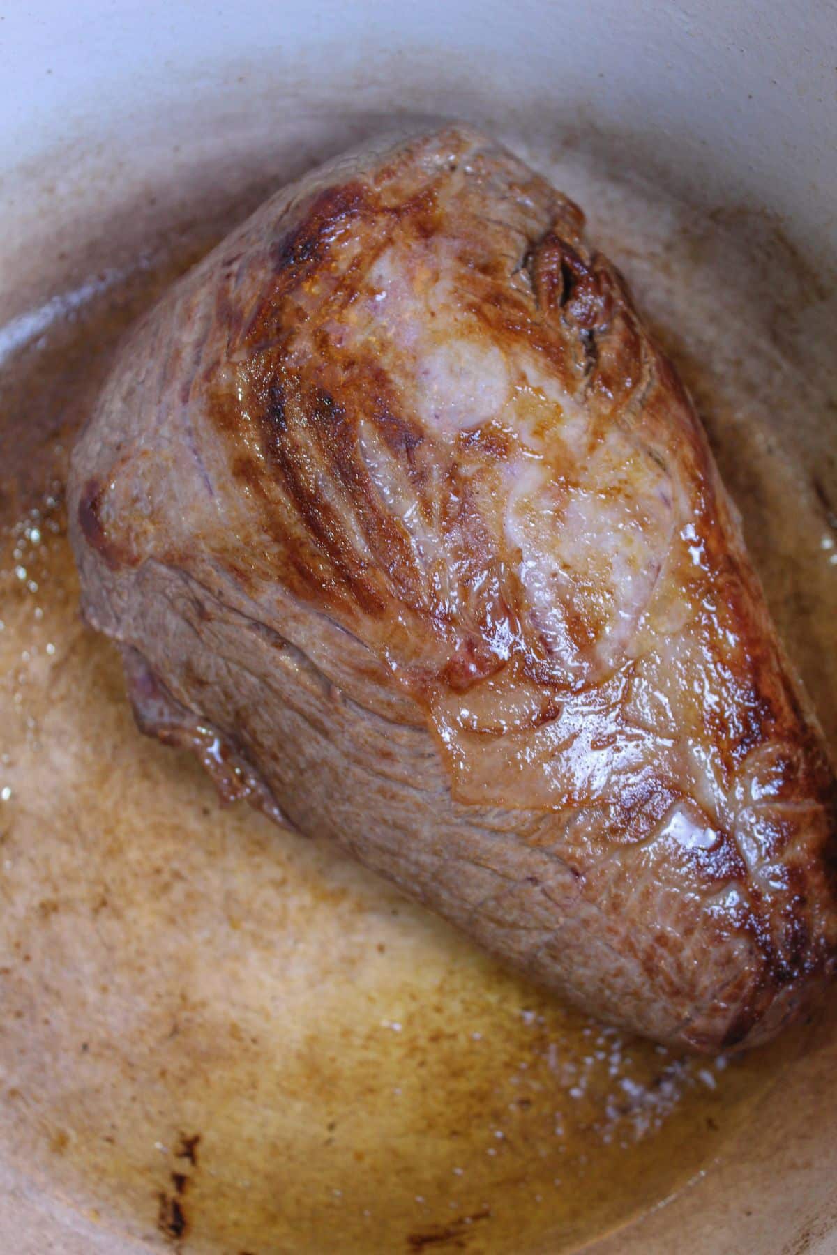 roast being seared on all sides in a large pot.