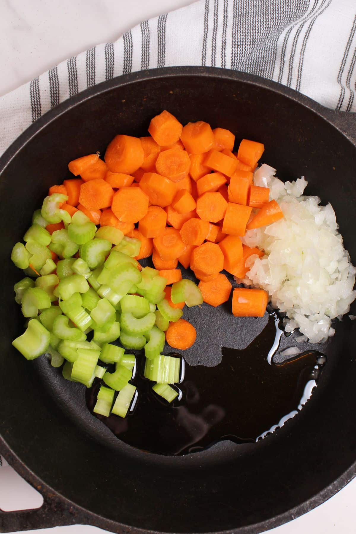 celery, carrots, and onions in a cast iron skillet to be sauteed.