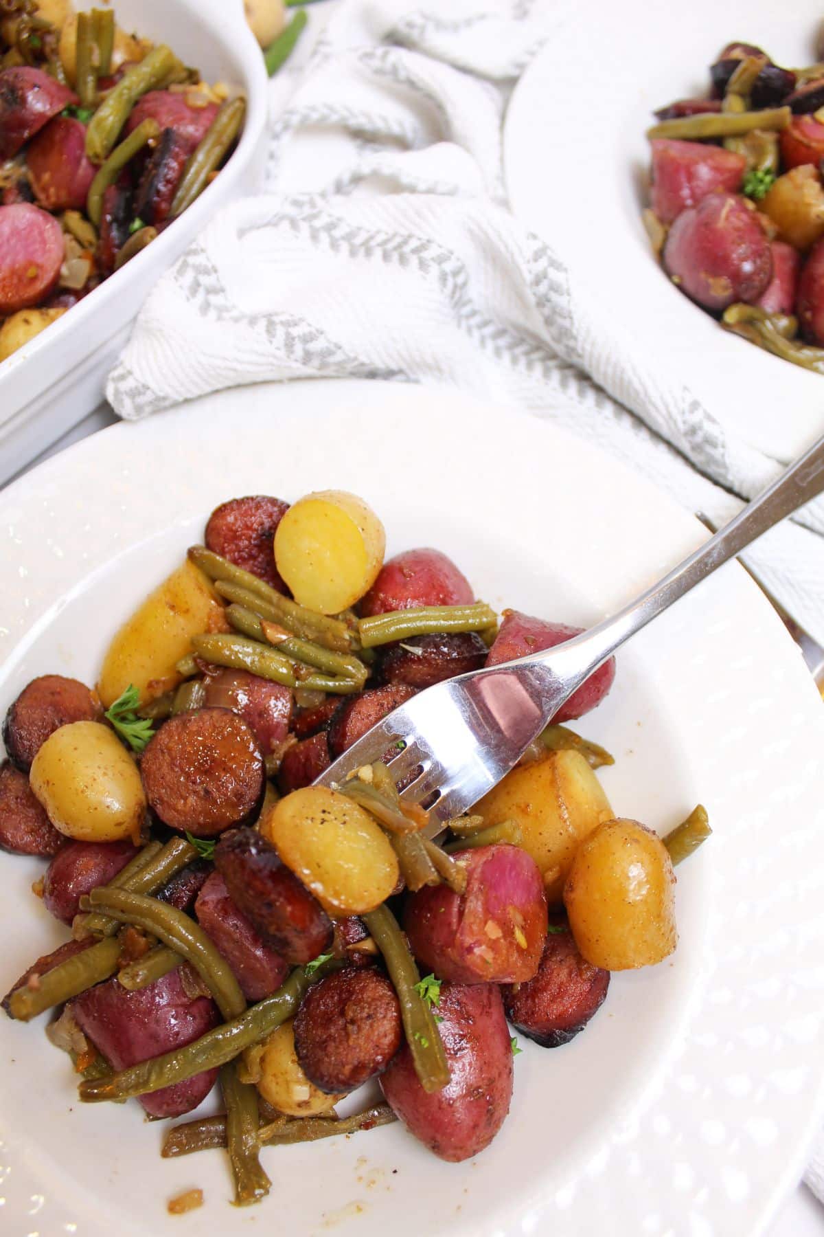 bowl full of potatoes and smoked sausage on a table.