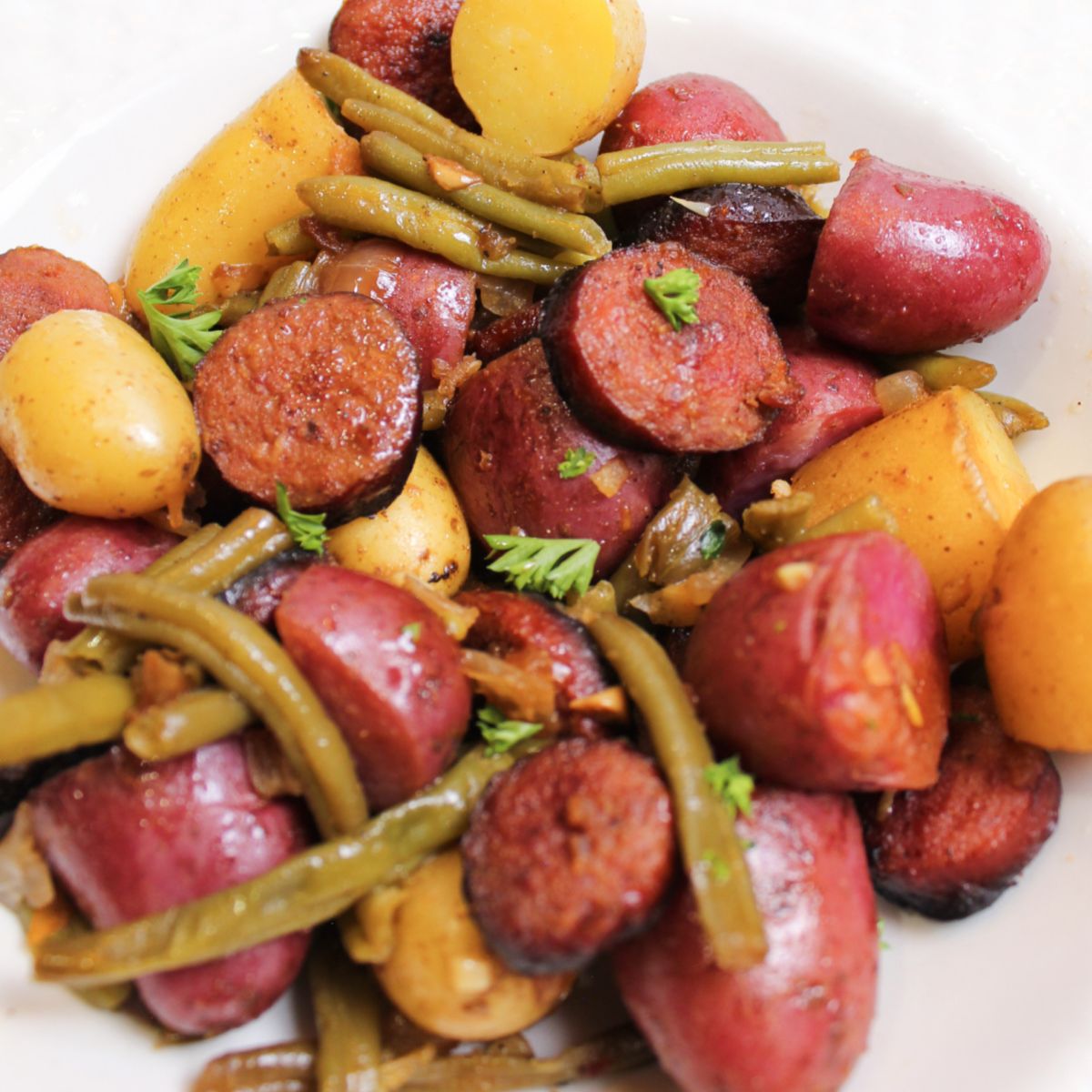 bowl full of potatoes and smoked sausage on a table.