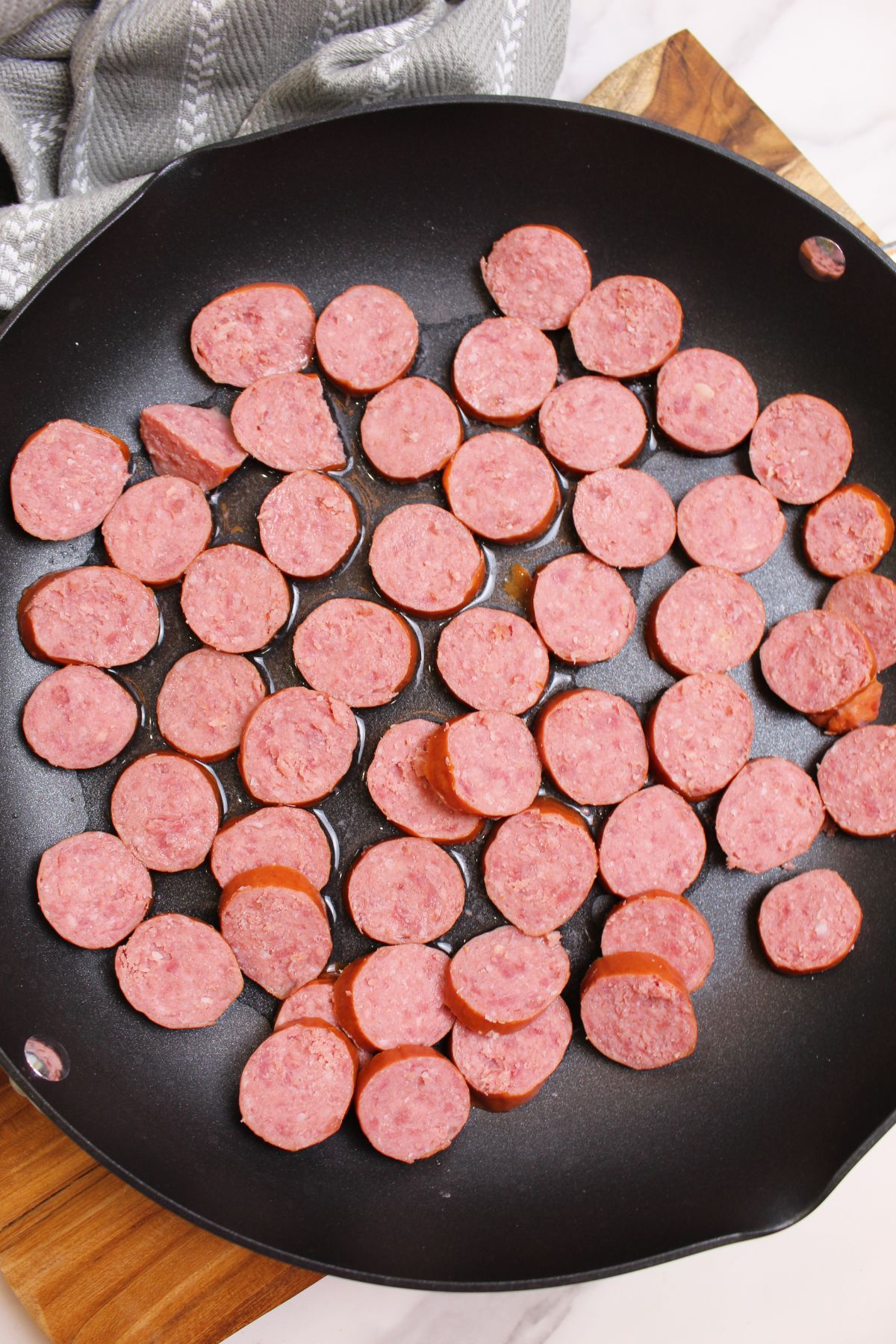 smoked sausage being browned in a skillet.