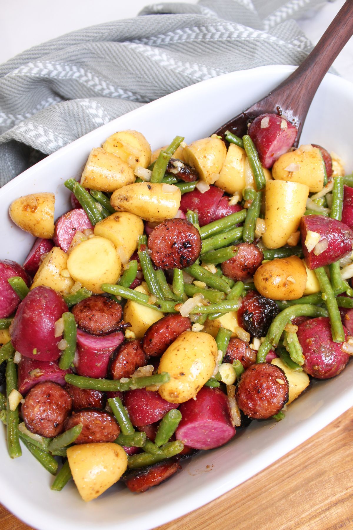 baking dish filled with sausage, potatoes, and green beans ready for serving.