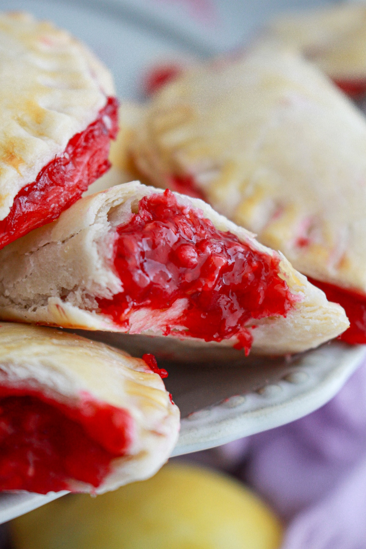 raspberry hand pies cut in half on a plate.