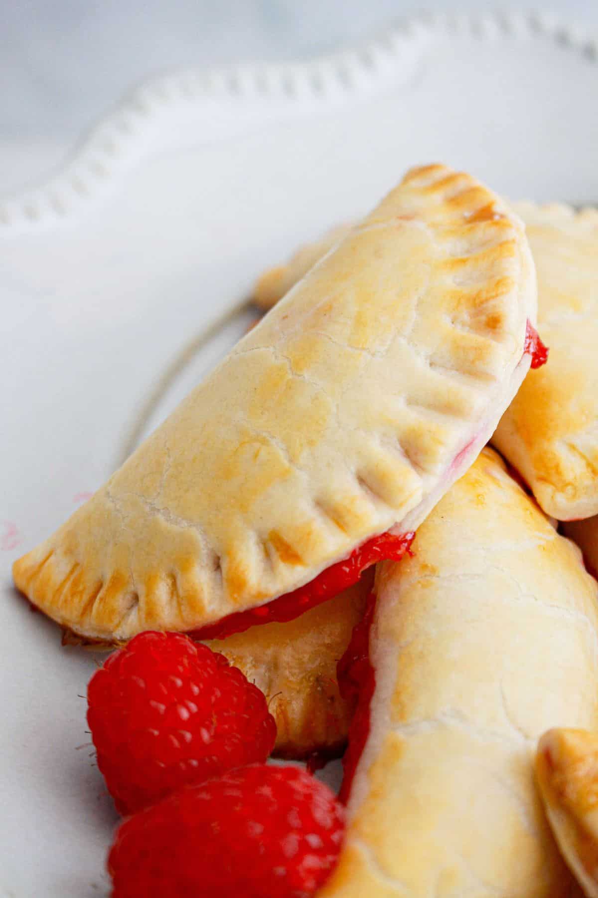 raspberry hand pies stacked on a plate.