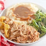 slow cooker Mississippi chicken on a plate with green beans and mashed potatoes.