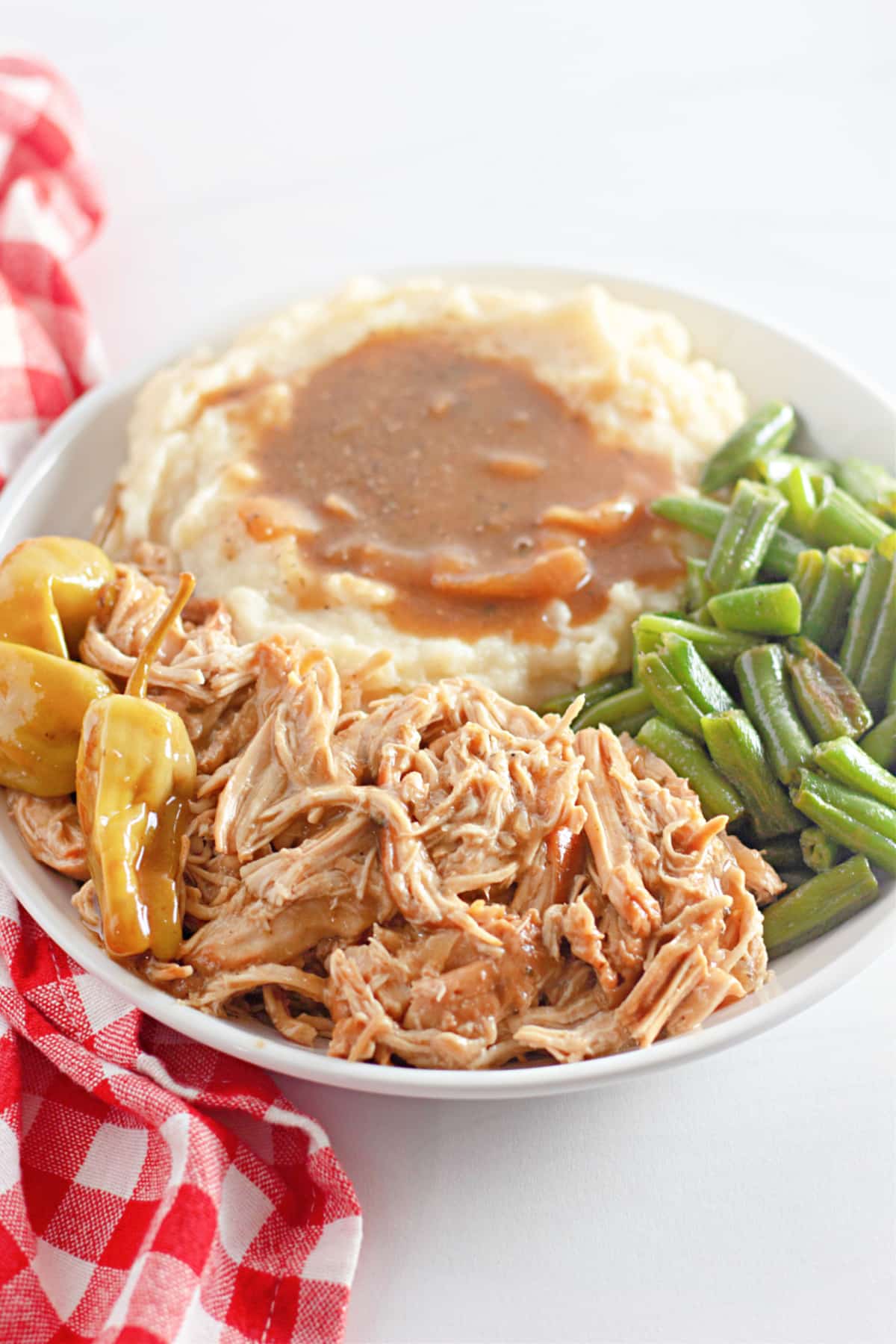 slow cooker Mississippi chicken on a plate with green beans and mashed potatoes.