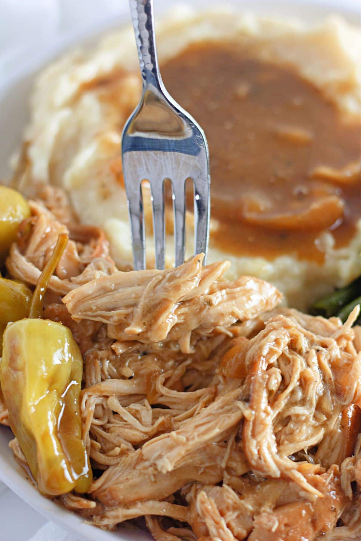 slow cooker Mississippi chicken on a plate with green beans and mashed potatoes.