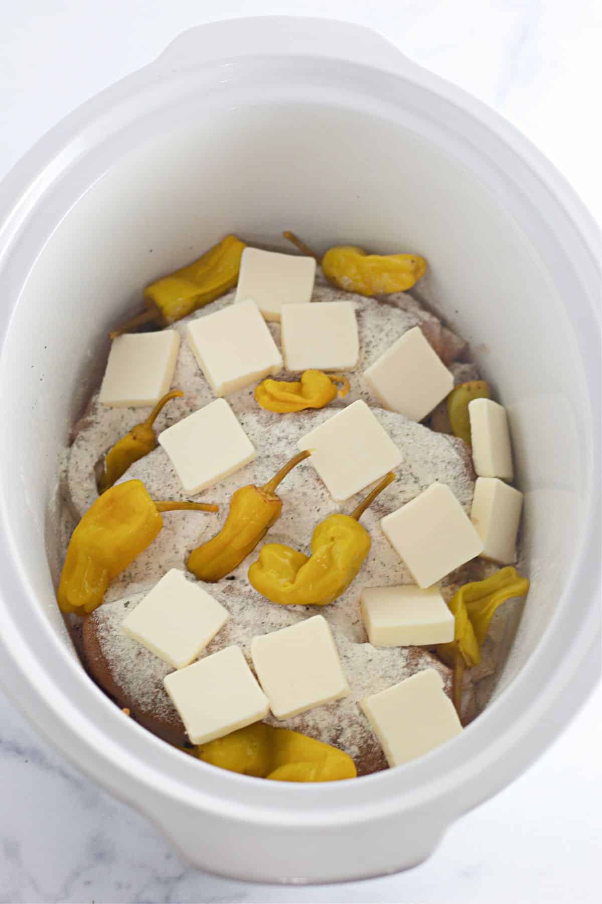 chicken, peppers, butter, ranch seasoning, and au jus mix in a slow cooker.
