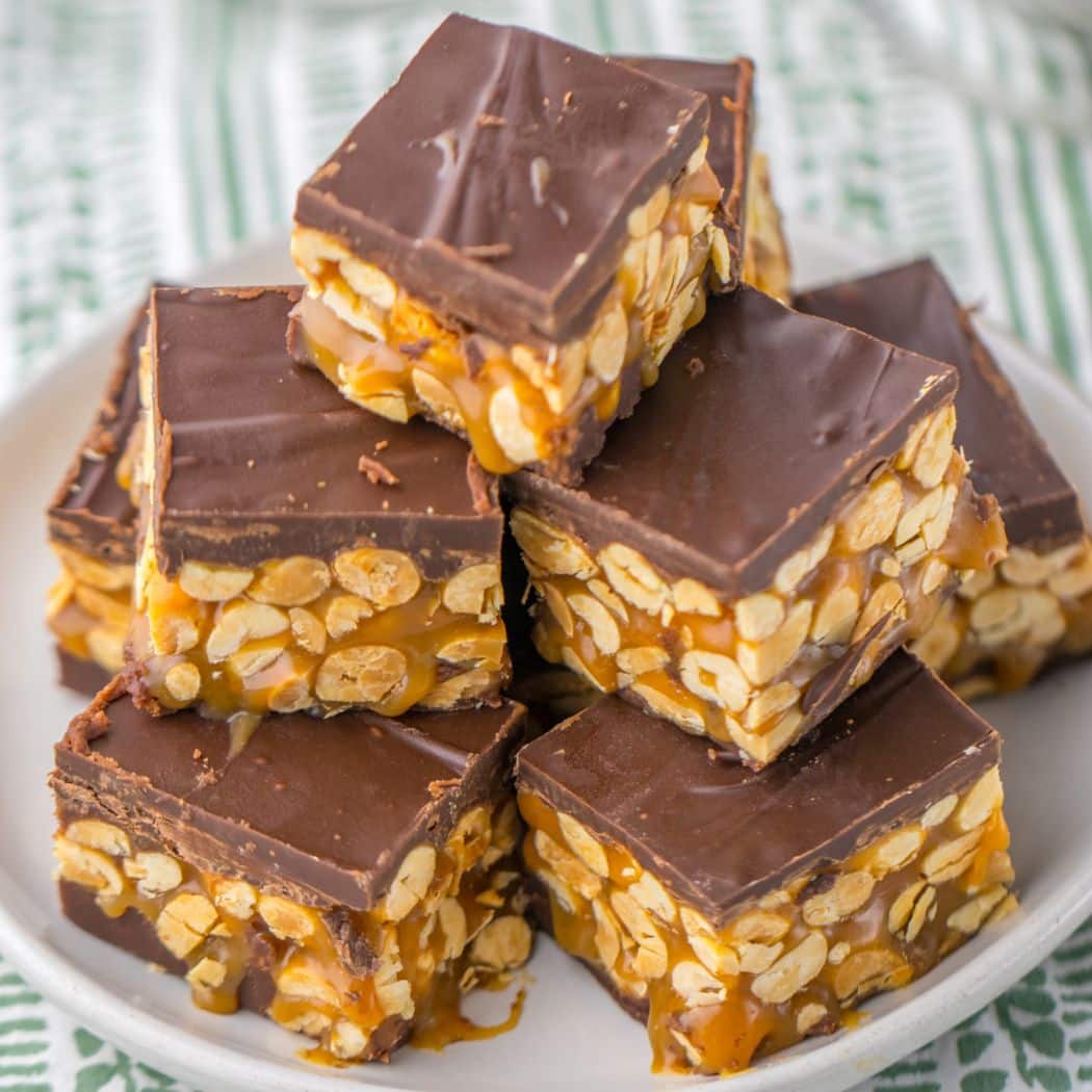 pieces of snickers fudge stacked in a pyramid on a plate.