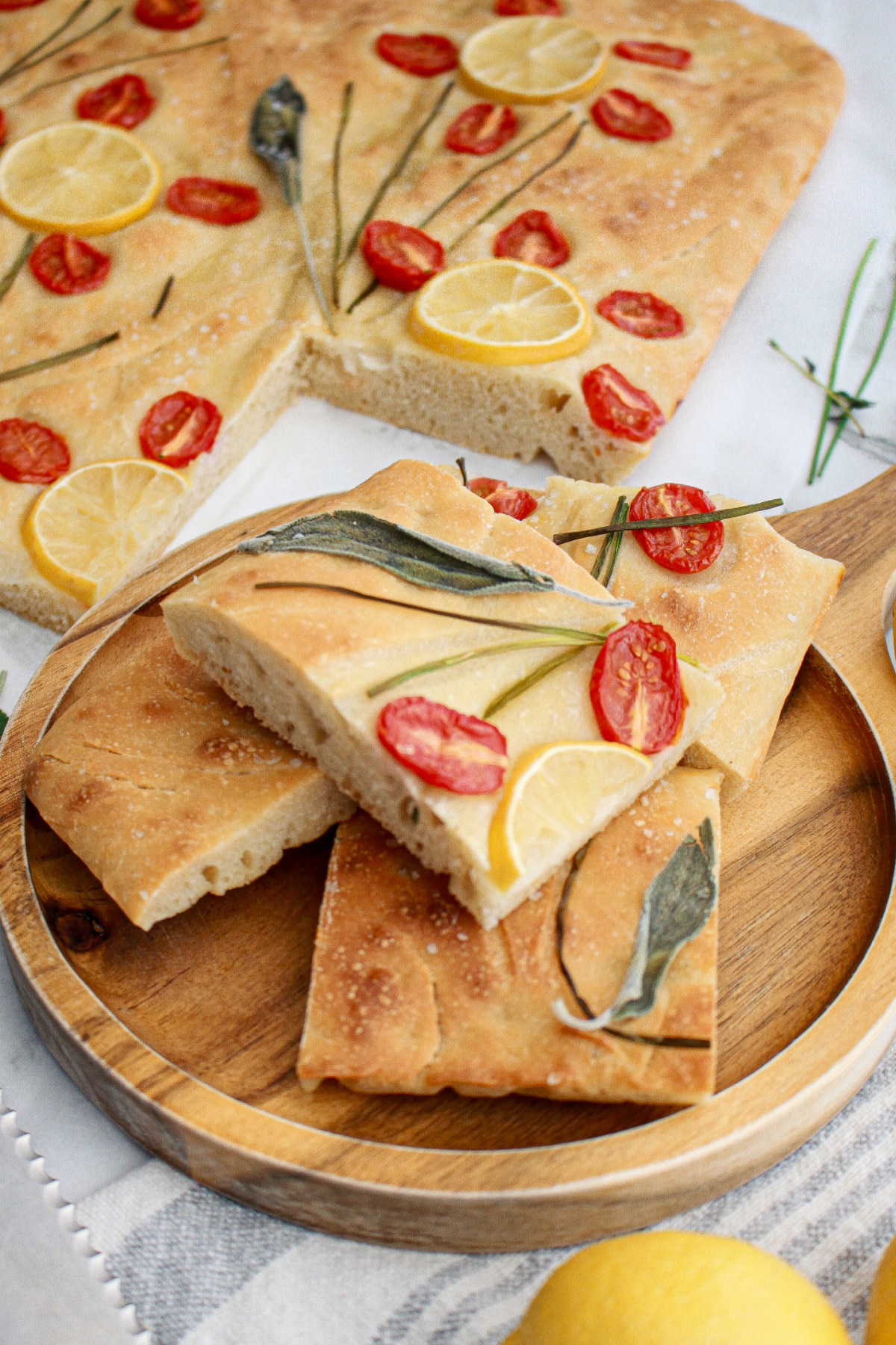 four pieces of tomato focaccia bread stacked on a wooden cutting board.